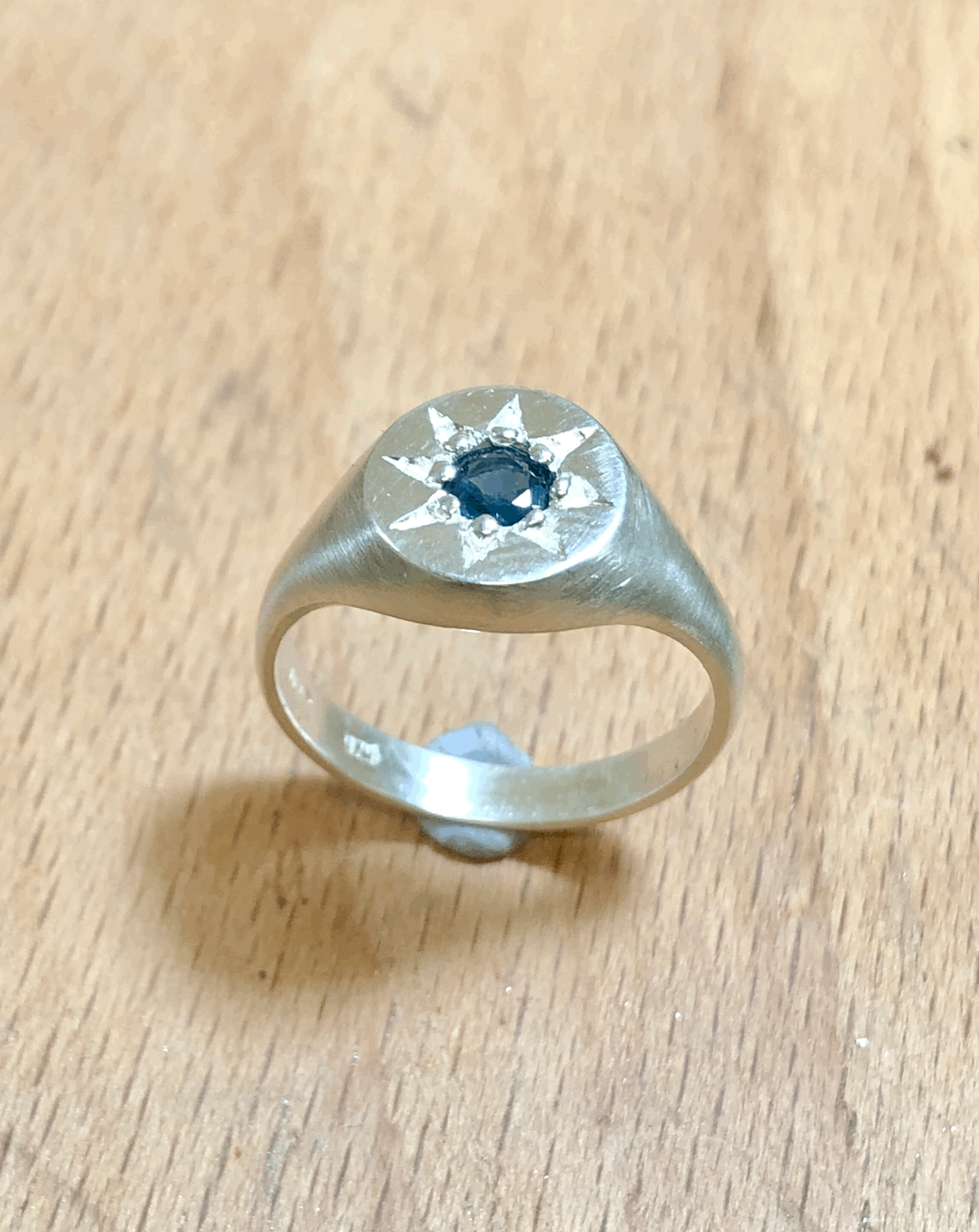 Close-up of round blue sapphire set in 9mm sterling silver signet face, handcrafted in New Zealand