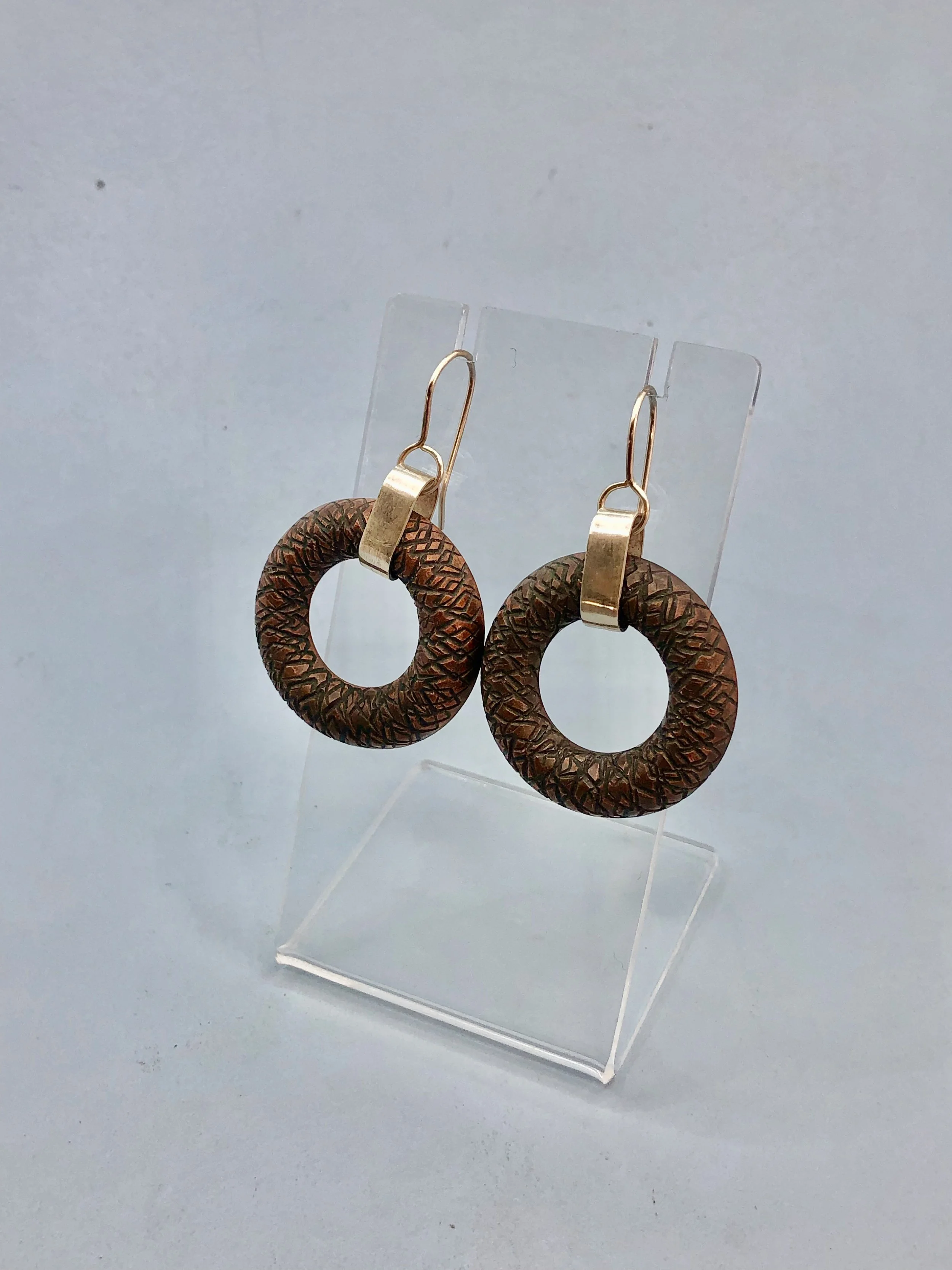 Textured copper donut shaped earrings shown hanging