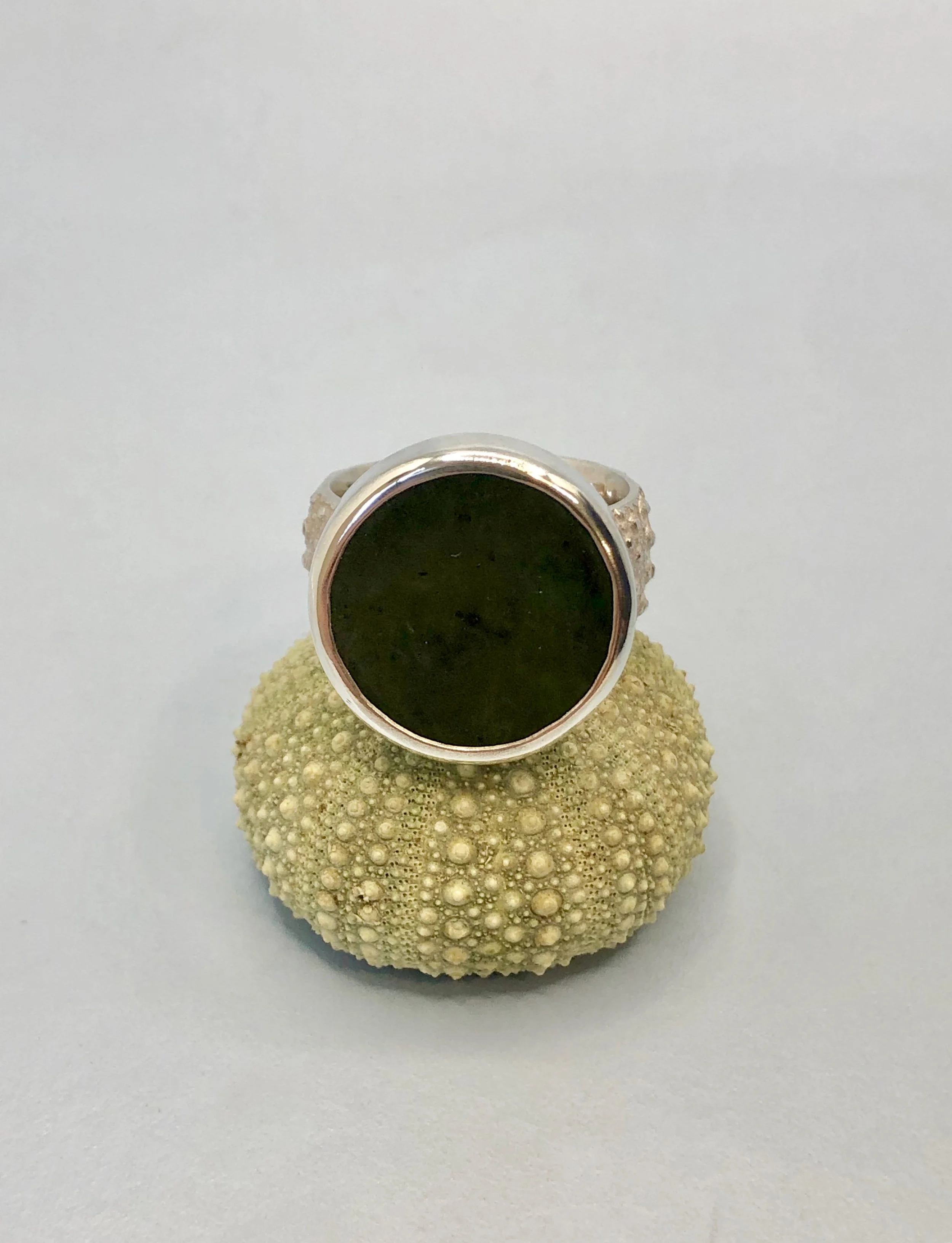 Front view of NZ greenstone disc ring sitting on a sea urchin