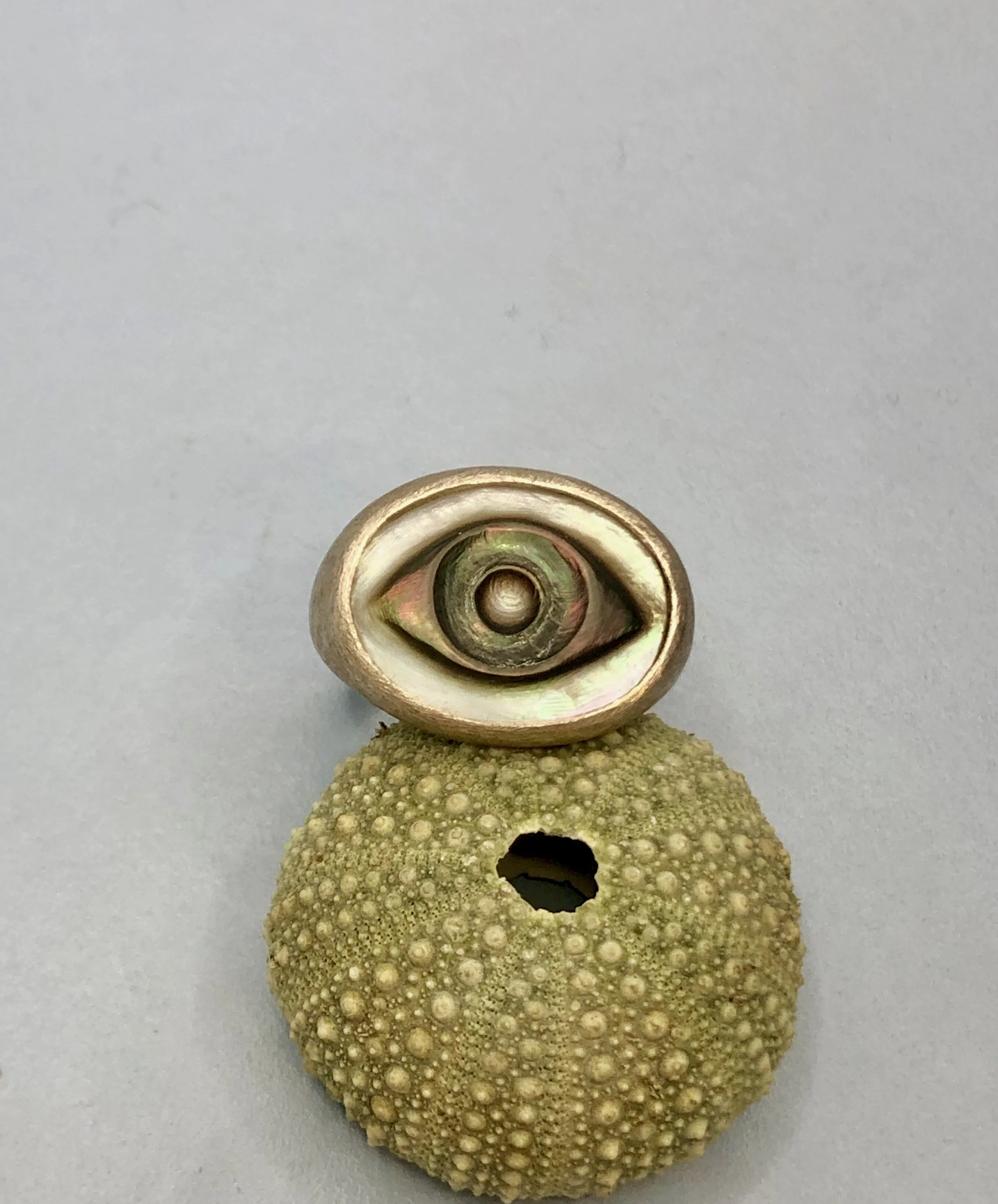 View of mother of pearl cameo ring resting on a kina shell, showing colour and iridescence of the pearl.