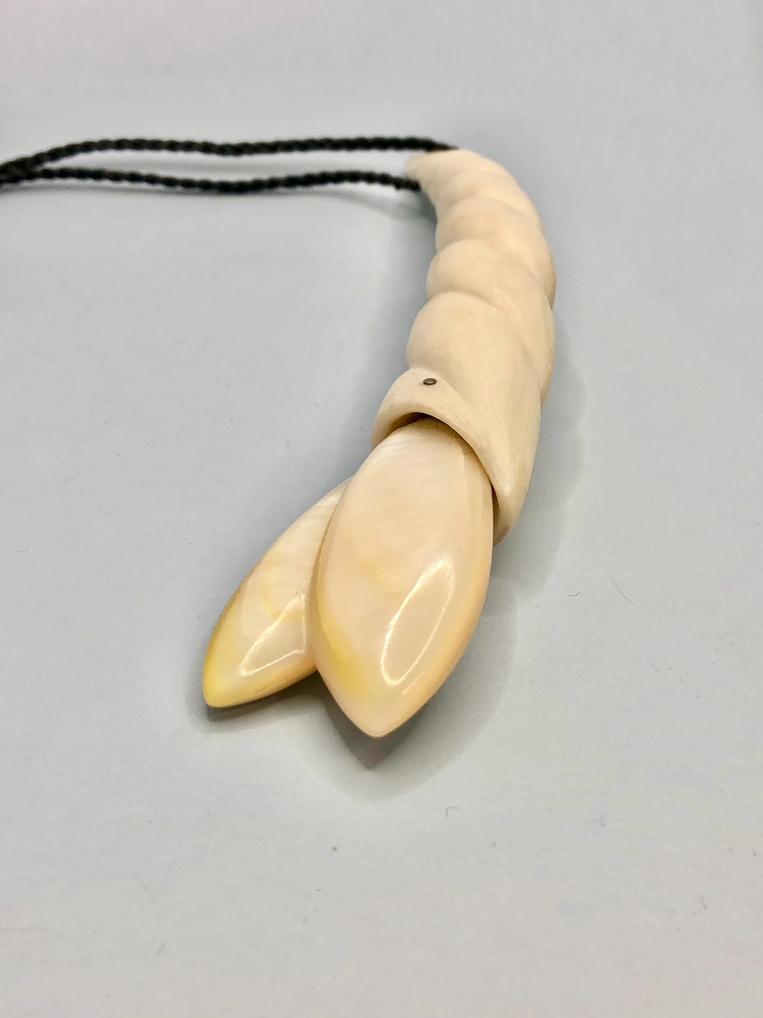 Close-up of mother of pearl flower bud and carved antler pendant