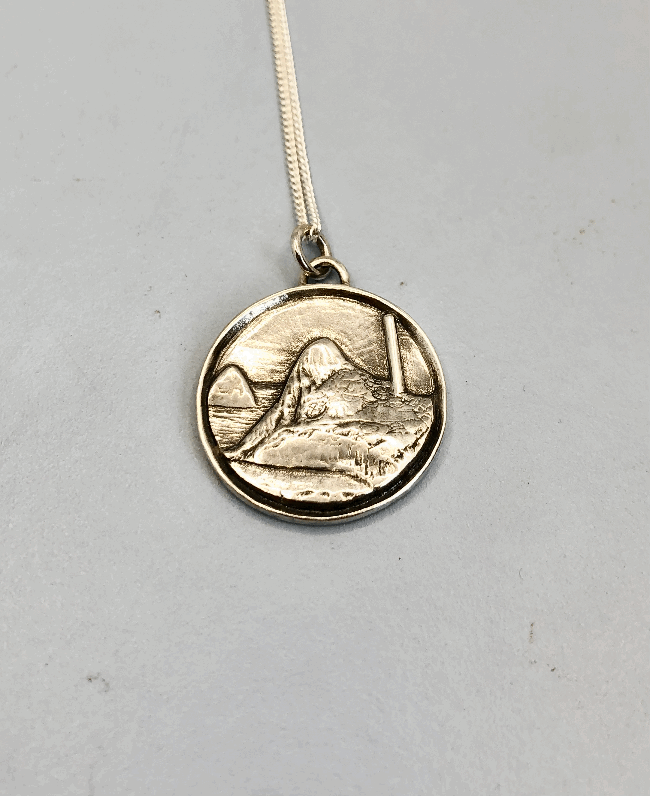 Sterling silver Paritutu and chimney medallion showing Ngāmotu coastal landscape. Rachel Lambert Jewellery