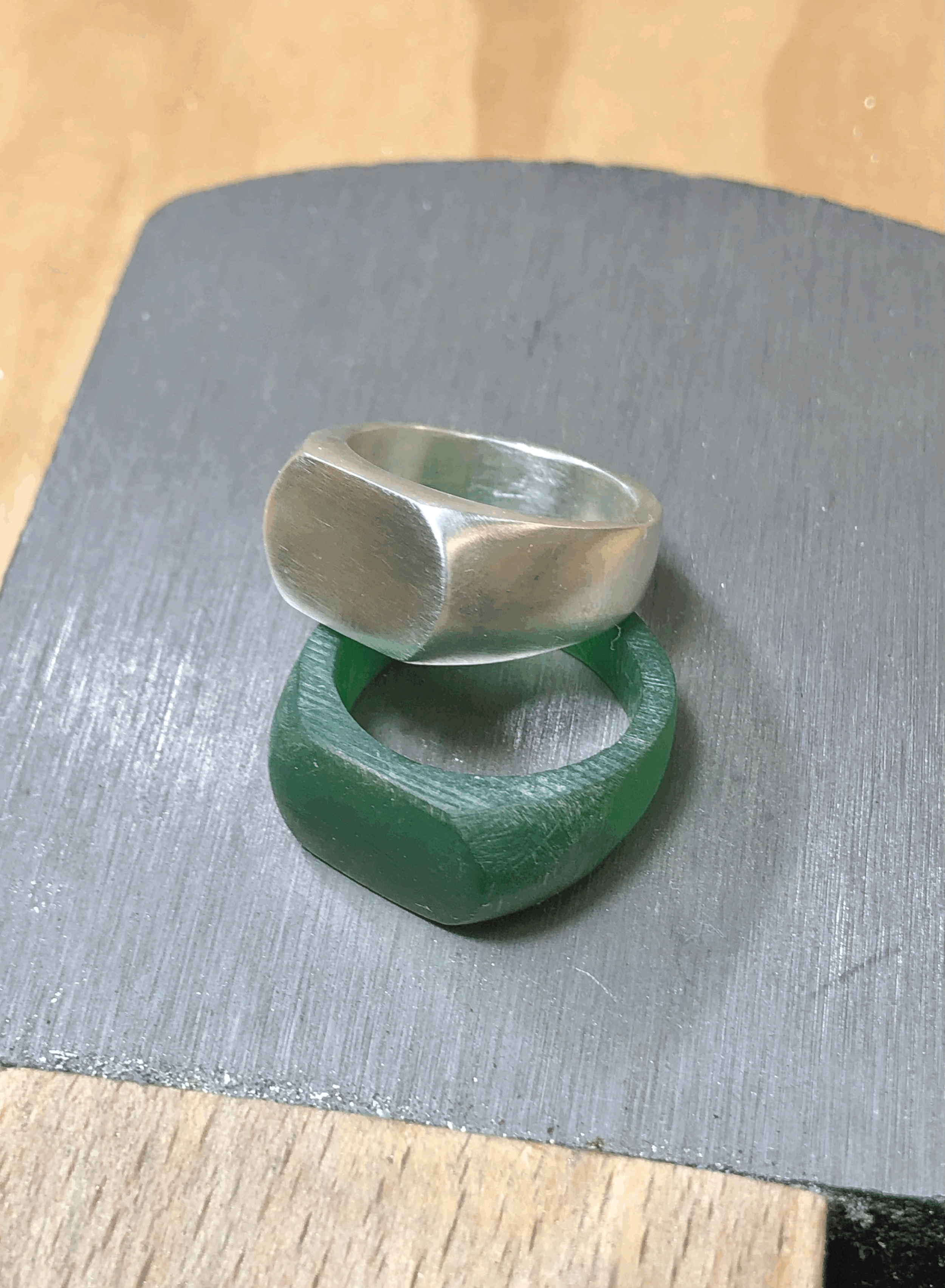 Sterling silver sand cast signet ring next to the wax carved master.