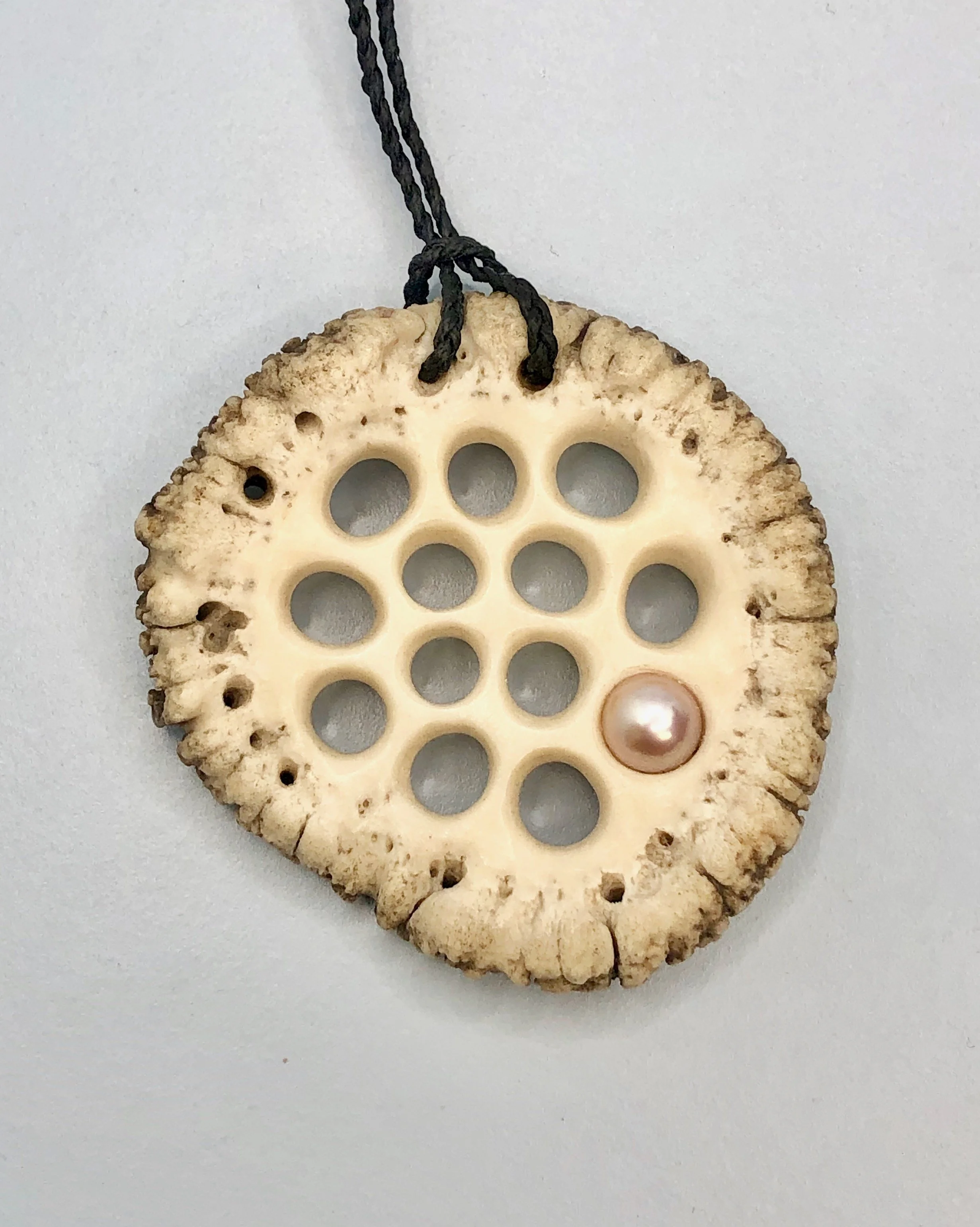Front view of lotus root inspired hand carved antler pendant with pearl attached