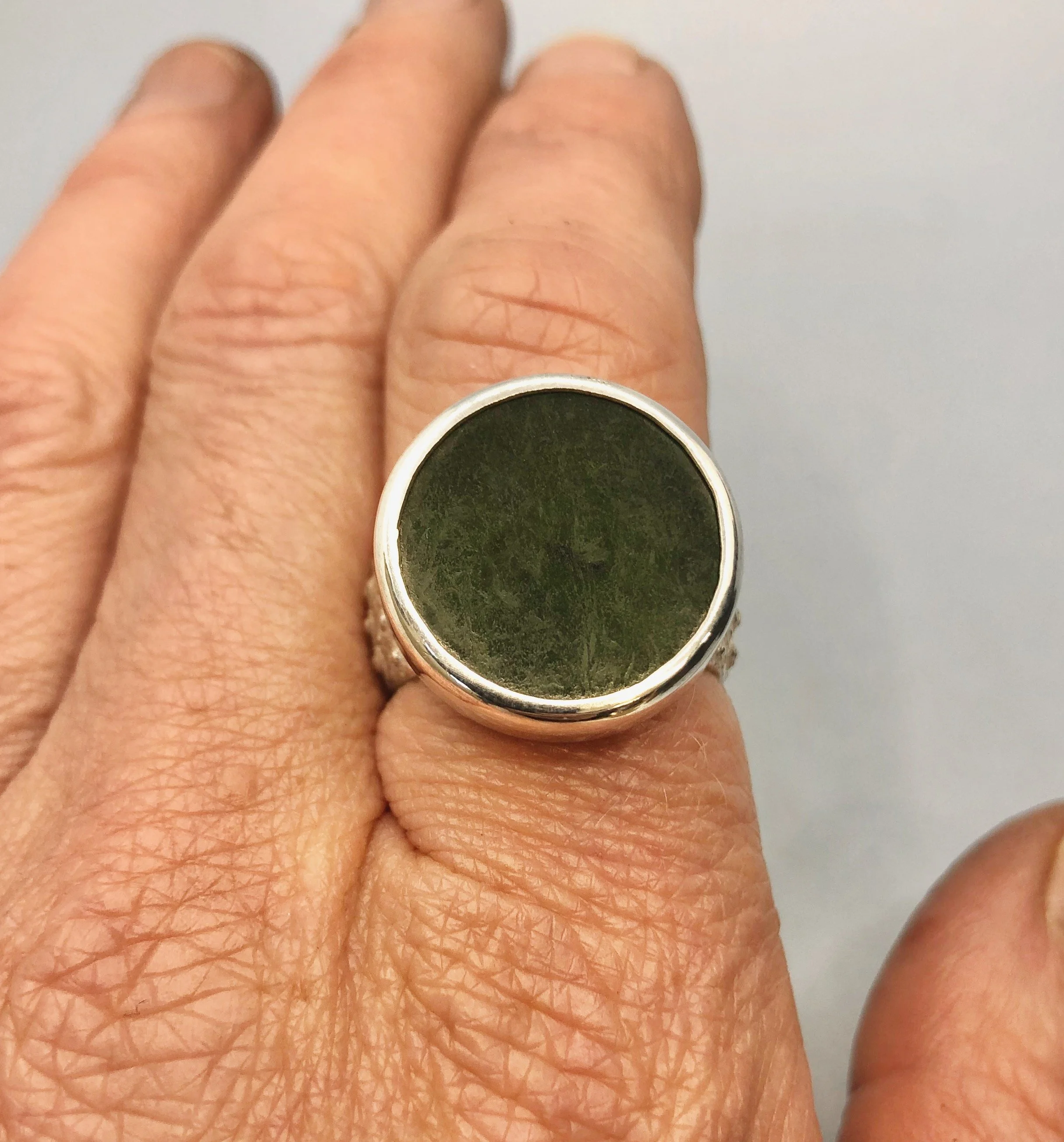 NZ greenstone disc ring shown worn on hand from the top.