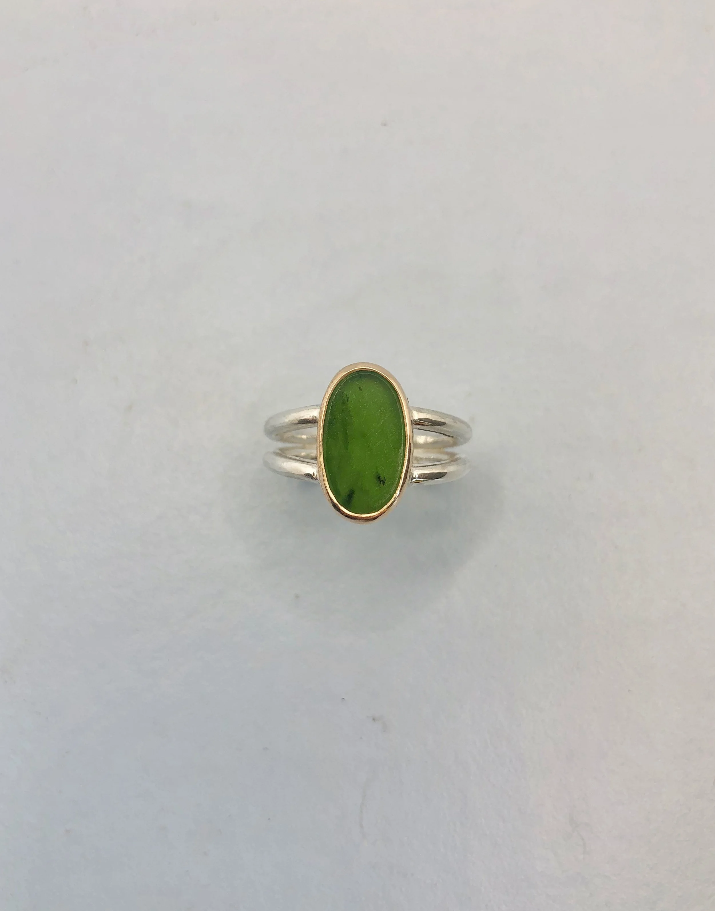 Sterling silver split-shank ring with hand-carved pounamu set in 9k yellow gold, front view