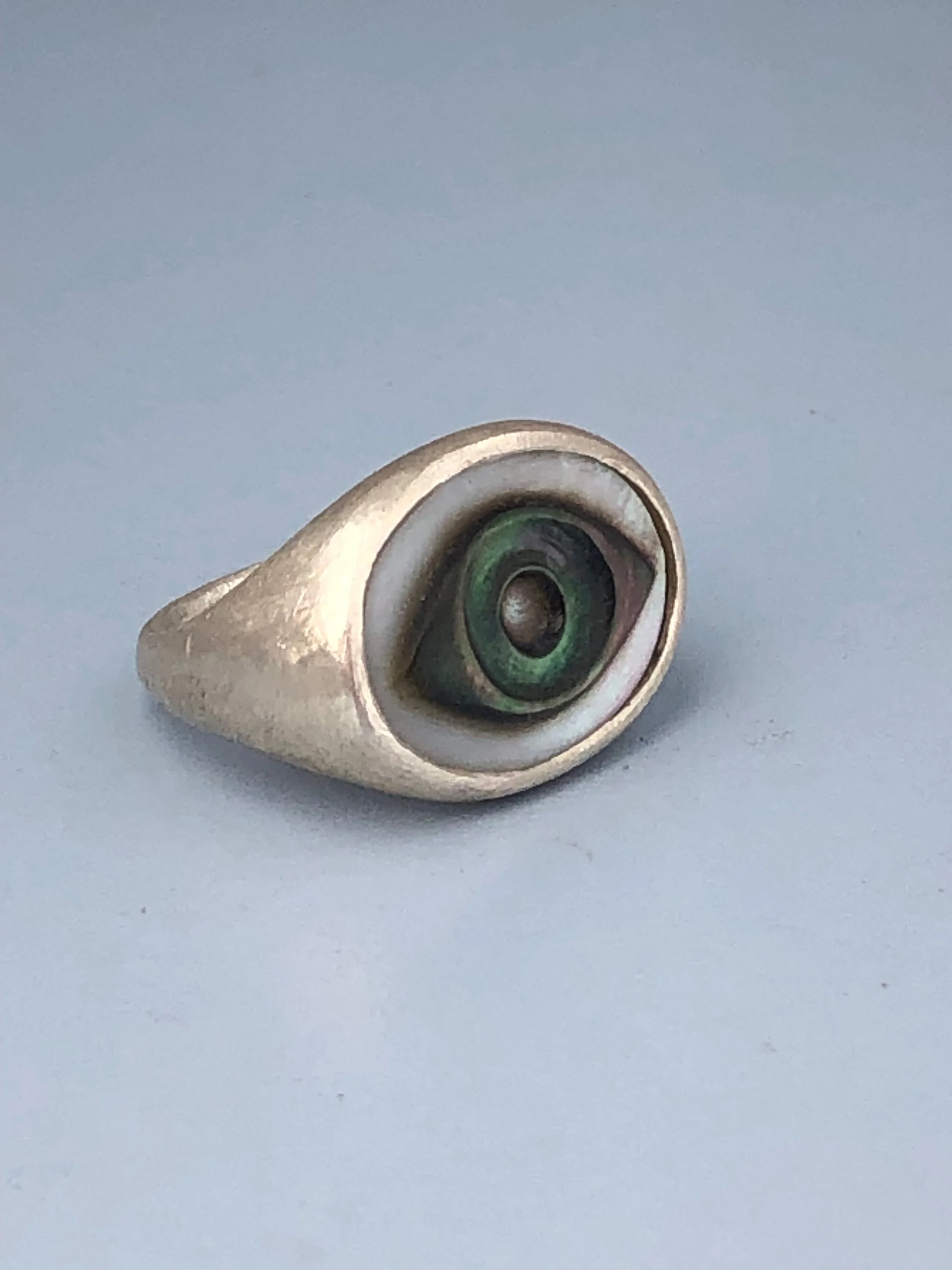Relief carved mother of pearl and sterling silver signet eye ring shown from the side.
