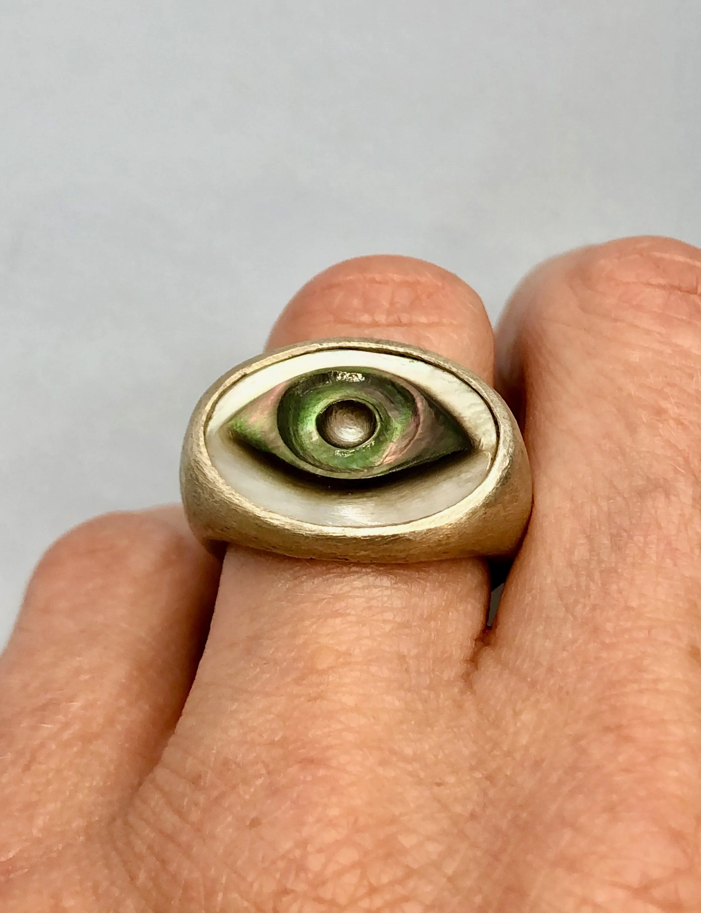 Carved mother of pearl cameo set in sterling silver being worn on a finger to show fit.