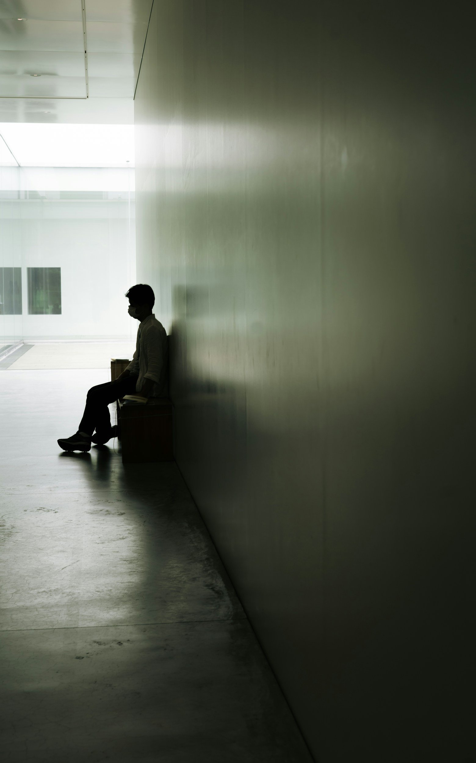 a man sitting. ona bench in a long hallway with dark contrasts, what is self worth, low self esteem