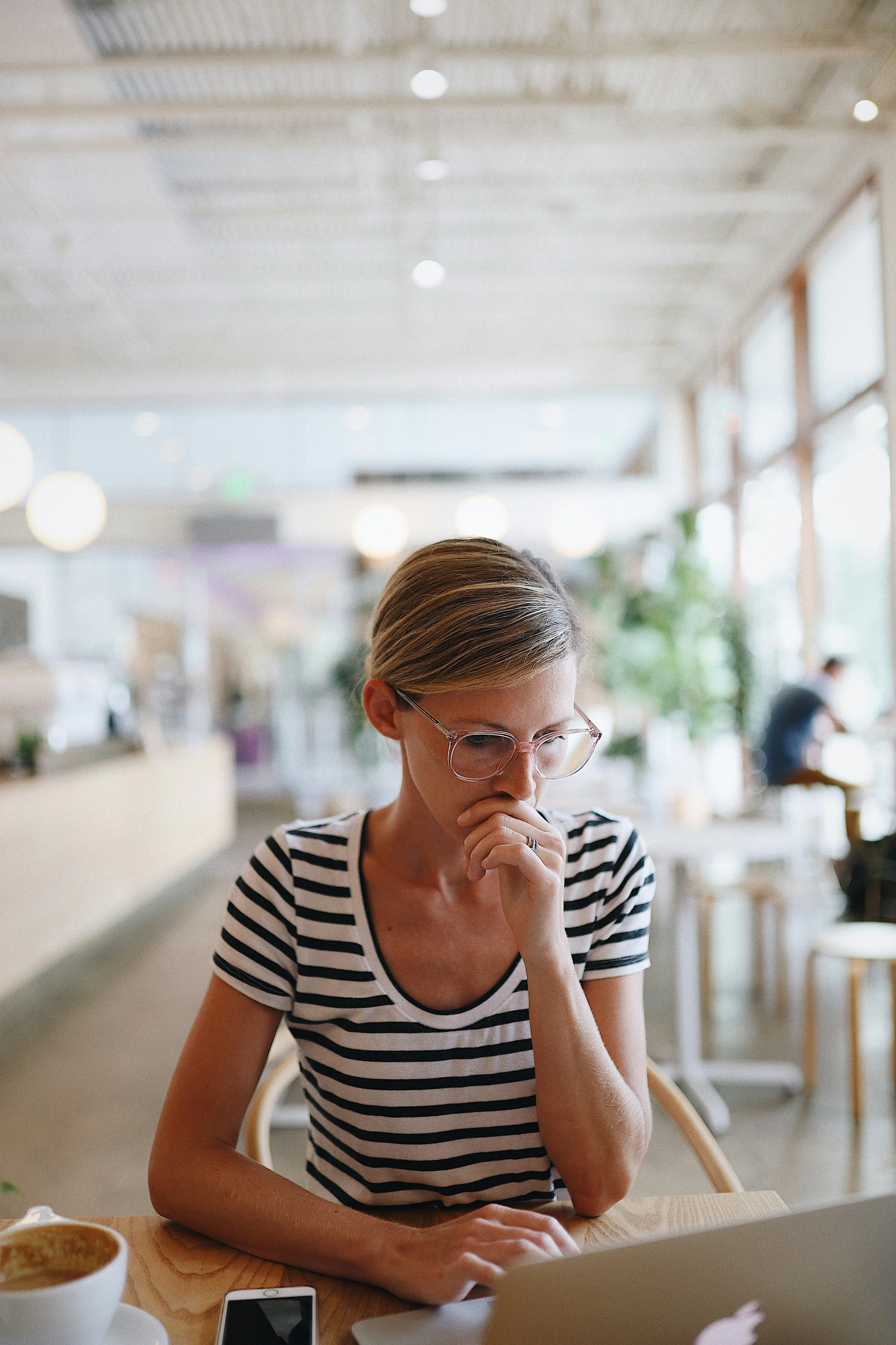 Woman sitting in a sunlit café reading thoughtfully, reflecting on her path through the stages of codependency recovery