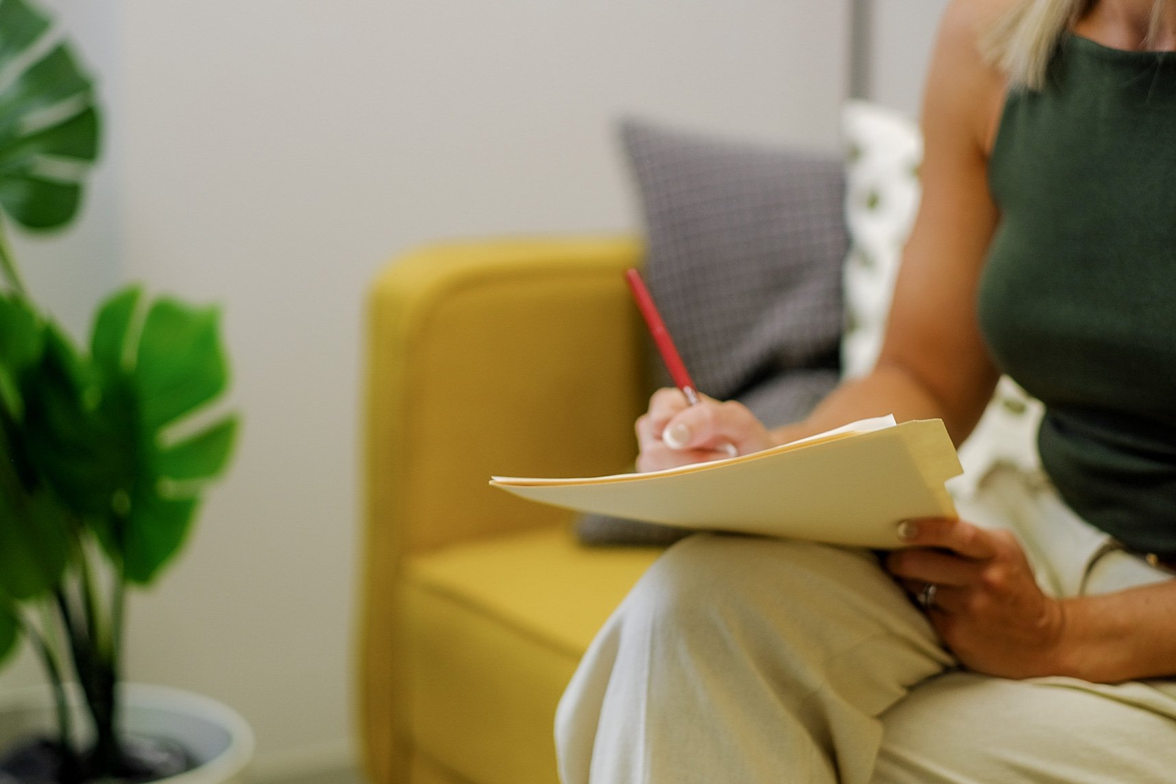 a woman sitting on a yellow couch taking notes in a therapy office,  what is self worth, low self esteem
