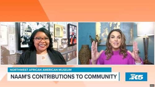 Two women speaking on a news broadcast about NAAM's contributions to the community, with displays and photos in the background of a museum.