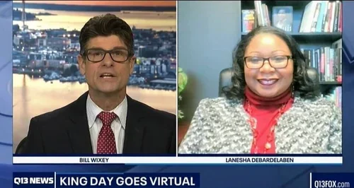 News broadcast with a male news anchor on the left and a female guest on the right, both visible in a split-screen format.