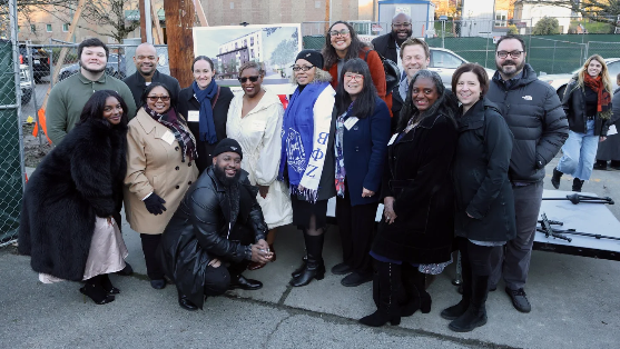 Group of diverse people standing outdoors at a basketball court, smiling at the camera.