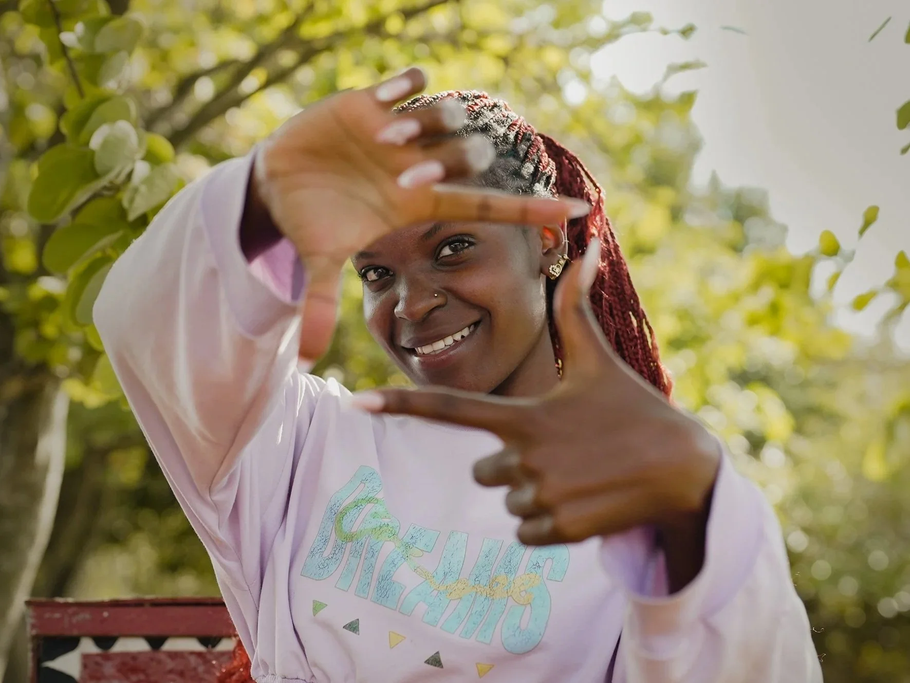 A young woman with her hands in front of her face making the camera/TV sign