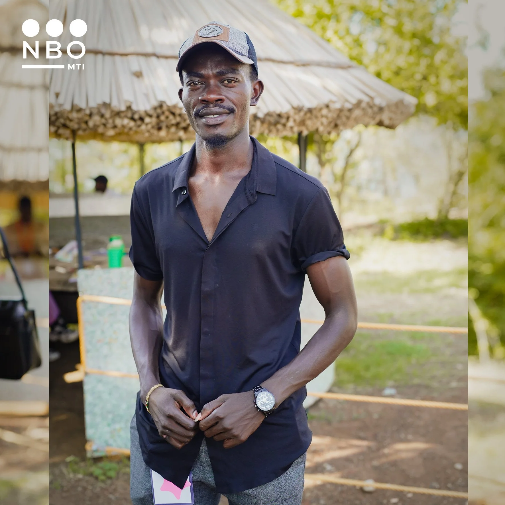 A young man named Apocrypher standing wearing a black shirt and a cap. An NMBO MTI alumni in Producing workshop in Kisumu