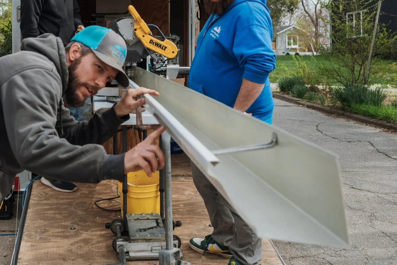 Gutter installers checking for perfection before securing custom fit seamless gutters on a house in the Oakley neighborhood of Asheville, NC