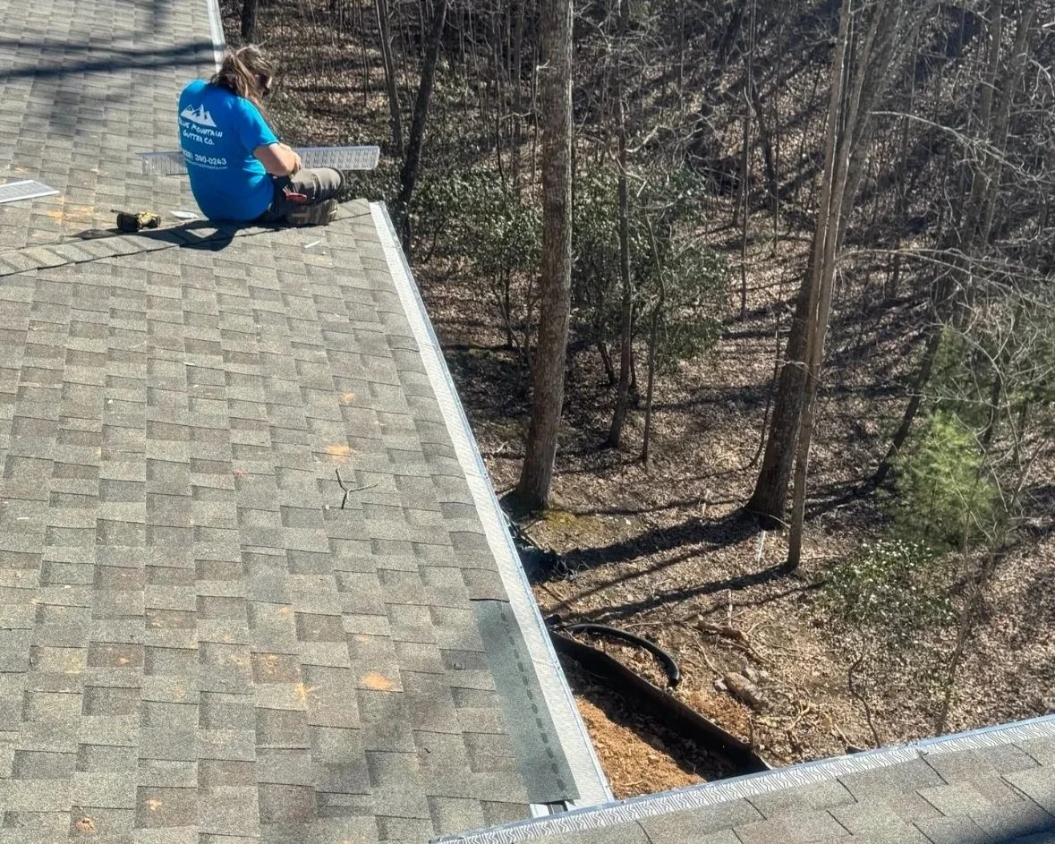 Gutter installer cuts LeafBlaster Pro micromesh gutter guard to size on this large 3 story roof in the Biltmore Lake neighborhood near Candler, NC