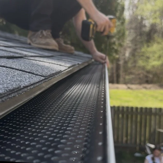 Gutter installer screws ShurFlo gutter guard onto a home in Arden, NC