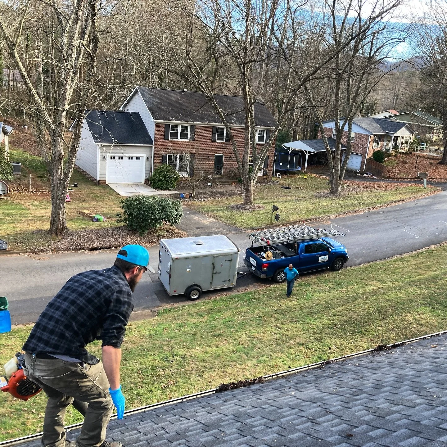 Crew member cleans out gutters in West Asheville neighborhood
