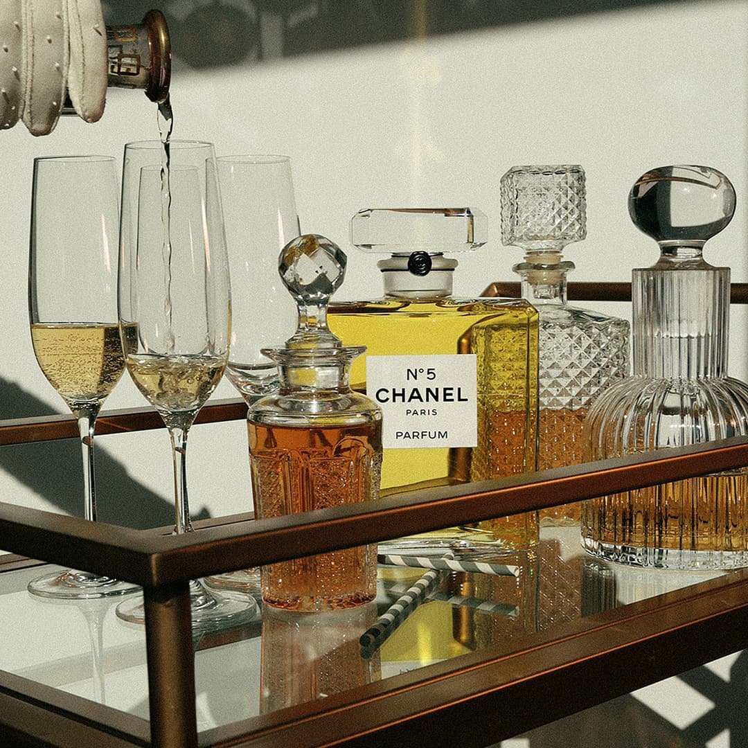 Collection of glass perfume bottles and champagne glasses on a mirrored tray