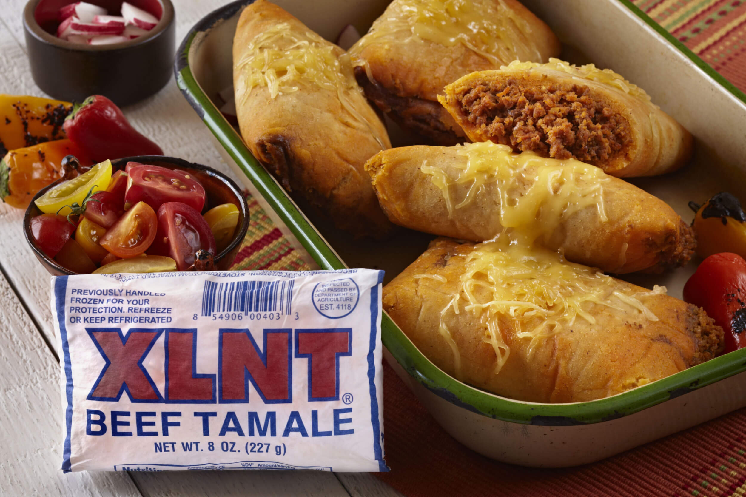 XLNT Foods 8oz Tamales topped with cheese served in casserole pan.jpg