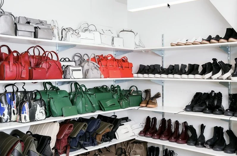 Shelves filled with various handbags and boots arranged by color and style.
