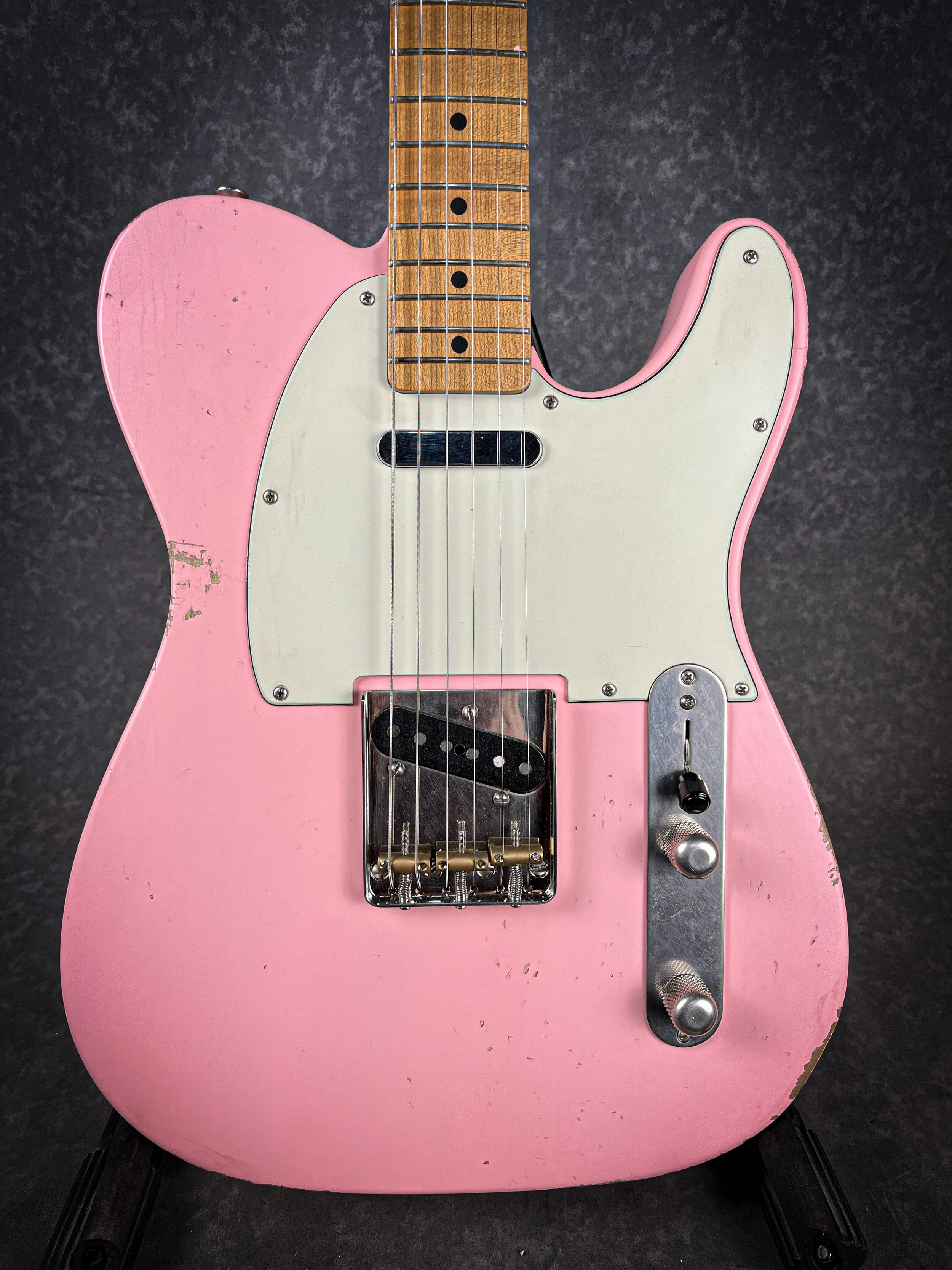 Pink LSL T Bone electric guitar with a white pickguard, wooden neck, and black hardware, showing signs of wear and scratches.