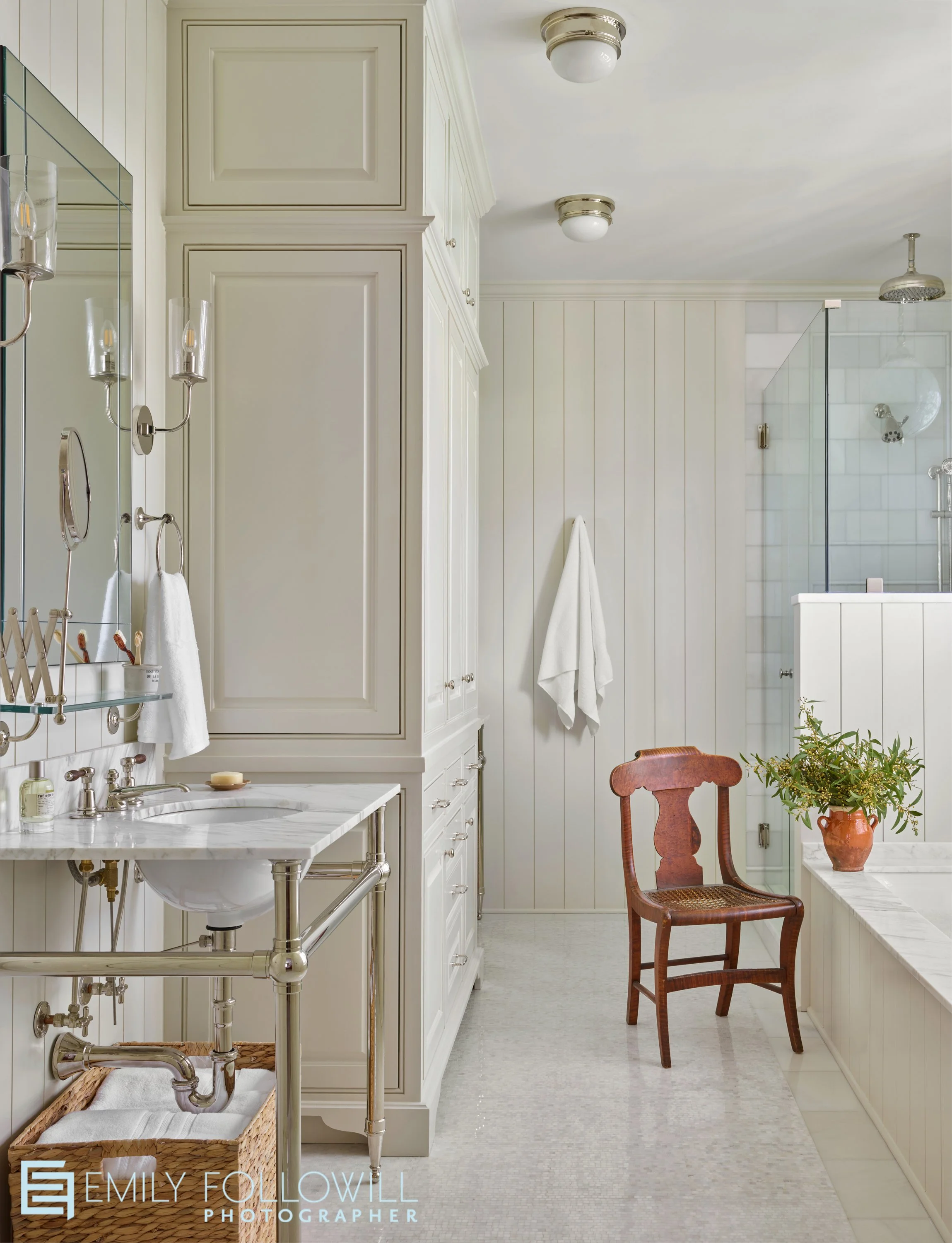 bright happy primary bathroom with a wooden chair to rest your glass of wine while taking a bath. Located in Atlanta Georgia. Designed by Lauren Elaine Interiors
