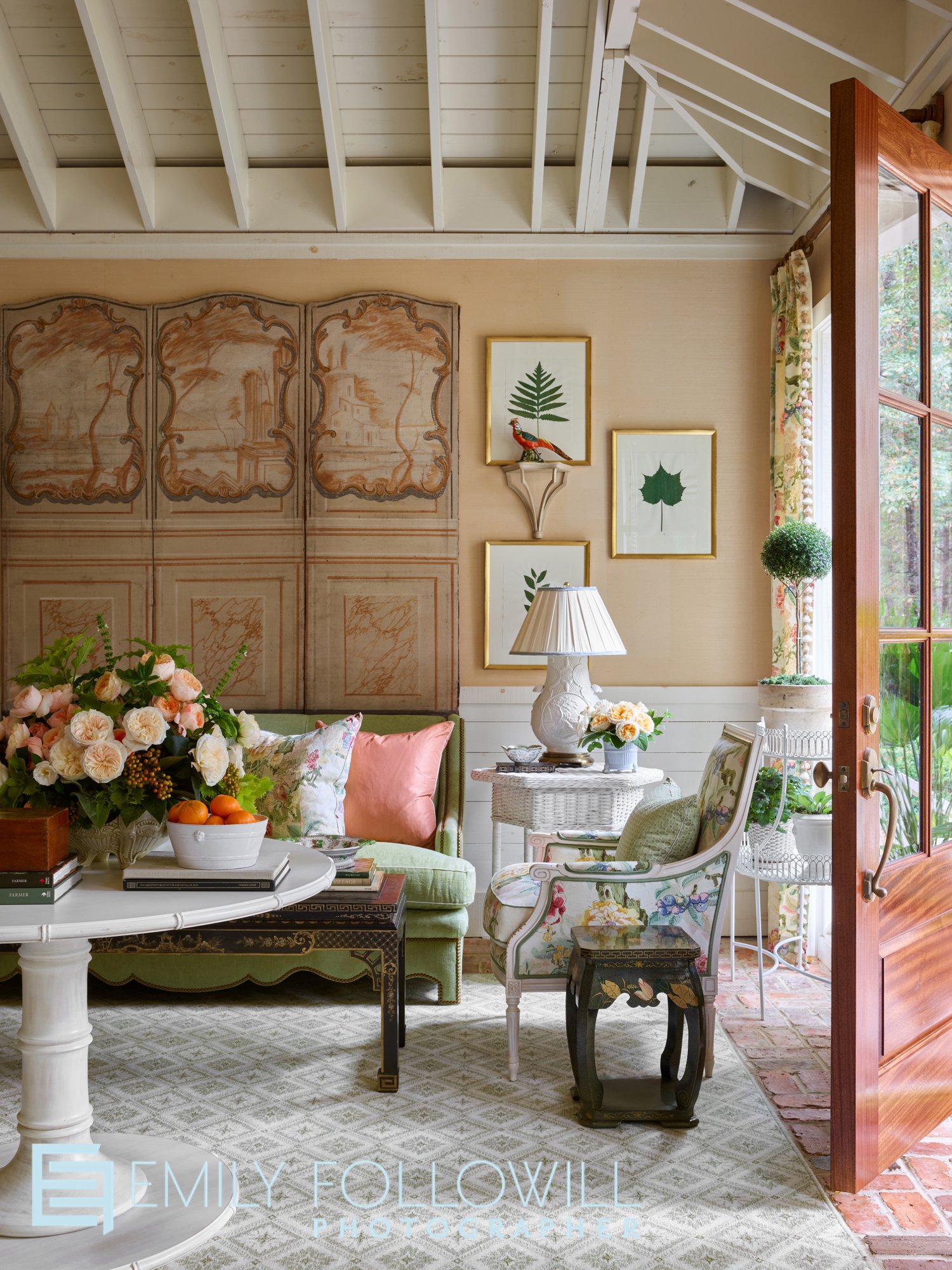 Bright peach living room, with a coral door open. Flowers from the garden sit atop the entry way table. Image from James Farmer's book "Home Again". Location: Perry Georgia 