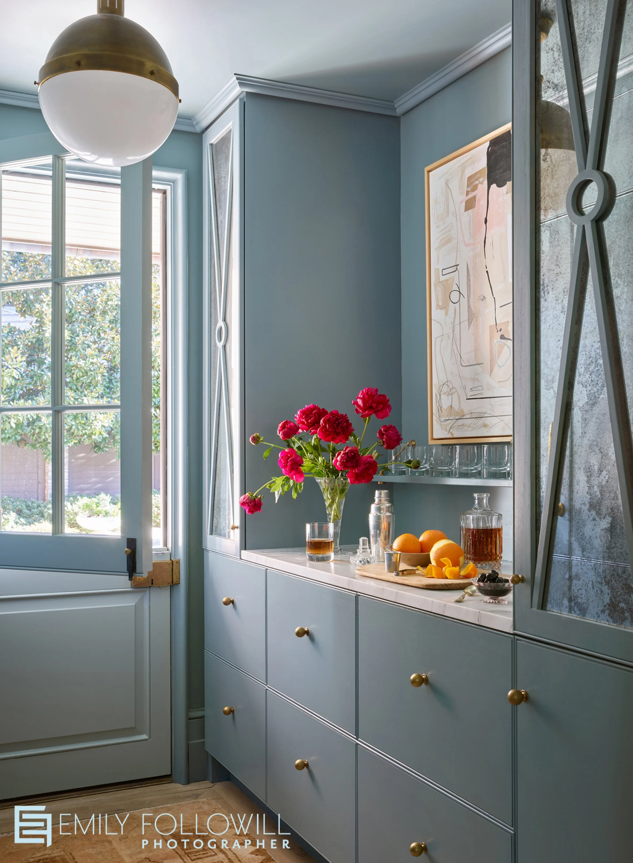 Light Blue butlers pantry with a dutch door. Bright fuschia peonies, oranges cut up to use in cocktails. mirrored cabinetry flanks the art hung above the bar. Location, Alabama