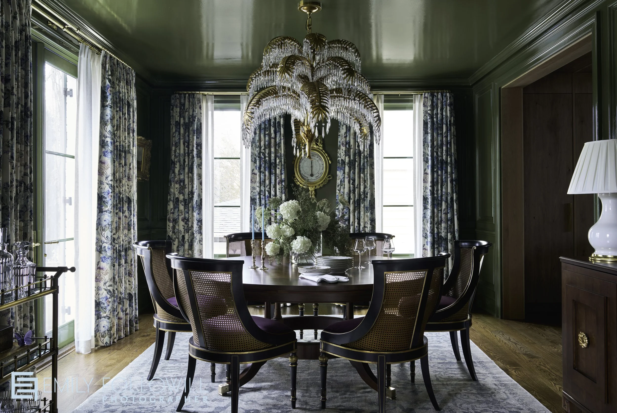 Beautiful dining room with green laquored walls and ceiling. A round wooden table sits under an ornate chandelier. With fresh cut hydrangea on the table. Location Atlanta Ga. Design by Easterling and Long 