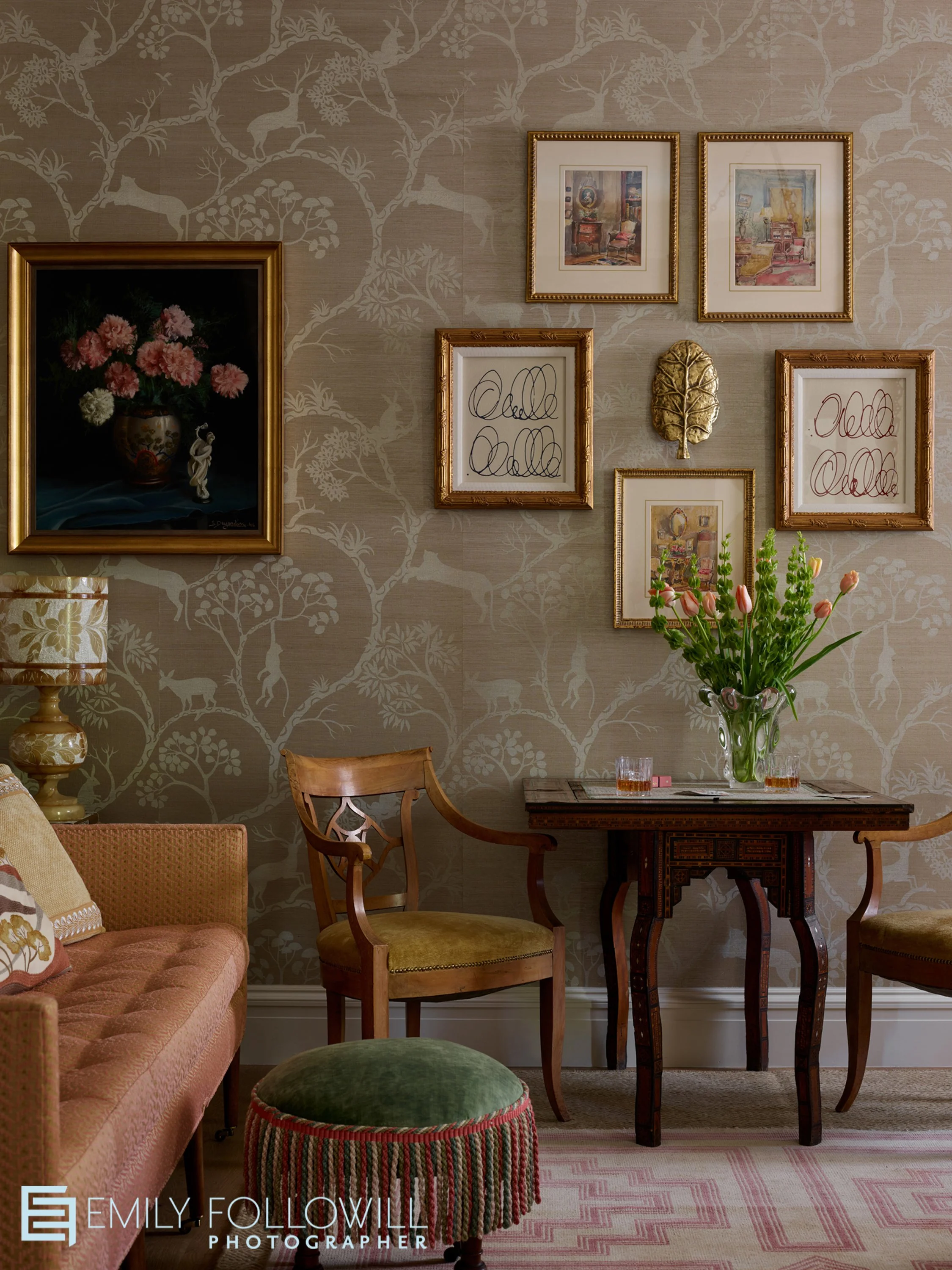 French inspired sitting room with a pink sofa. Gold framed art hangs on golden wallpaper. Design by: Alcott Interiors, for the Atlanta Homes & Lifestyles 2025 Southeastern Designer Showhouse. Location: Atlanta, Georgia