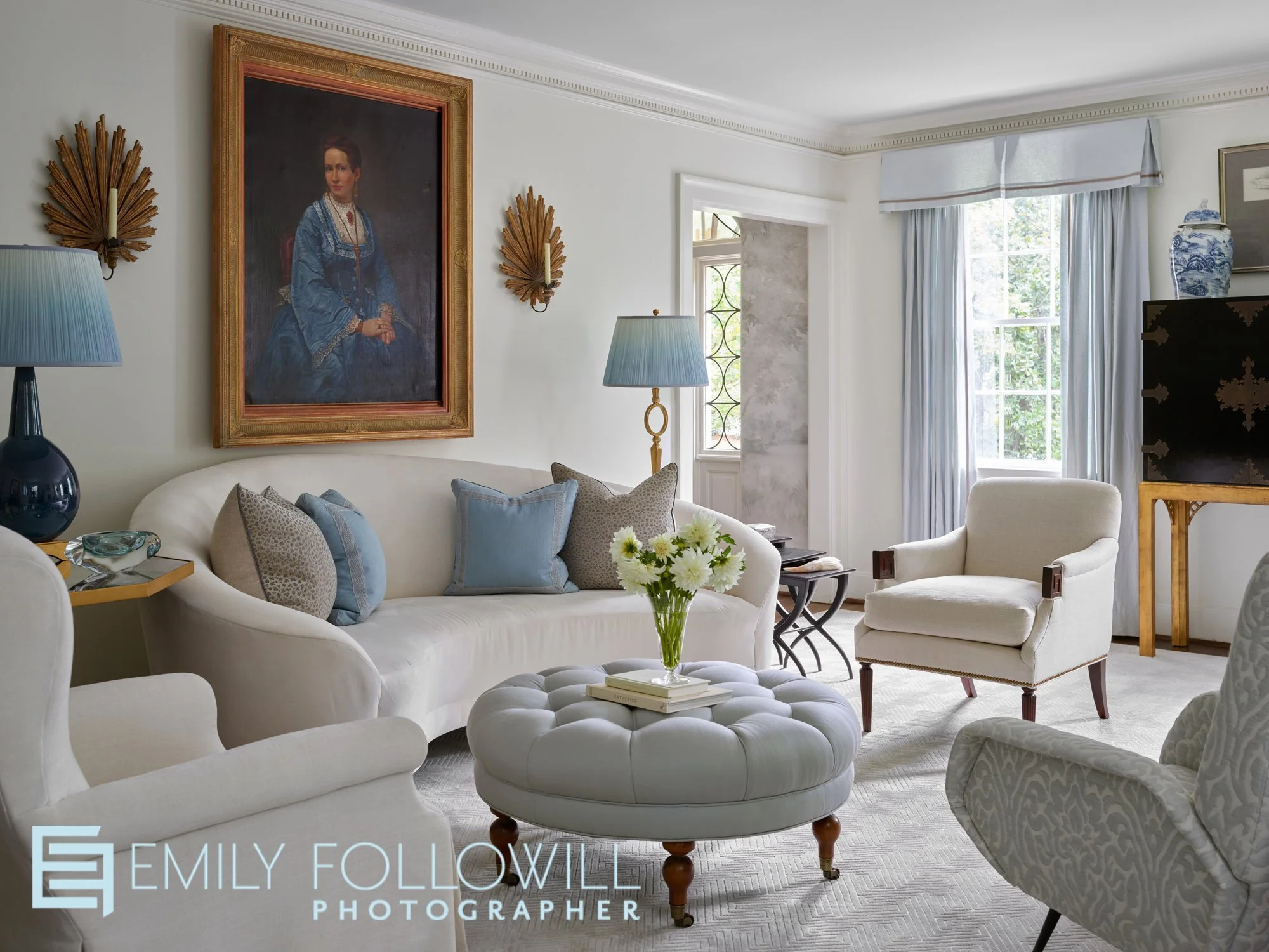 White airy modern living room with shades of blue in the furniture and fabrics. The view offers a peak into the entryway. Located in Buckhead Georgia. Designed by Phoebe Howard.