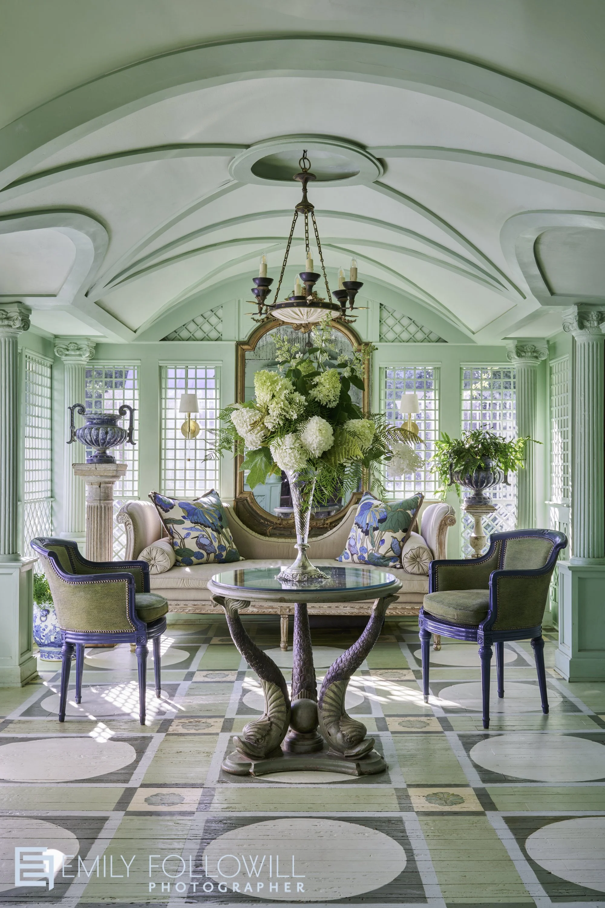 Ornate Green sunroom, with hand painted wooden floor. A large bouquet of hydrangea from the garden beyond sits on top of an antique table. This house is an historic home in Madision Ga, designed and lived in by Randy of Boxwoods atl.