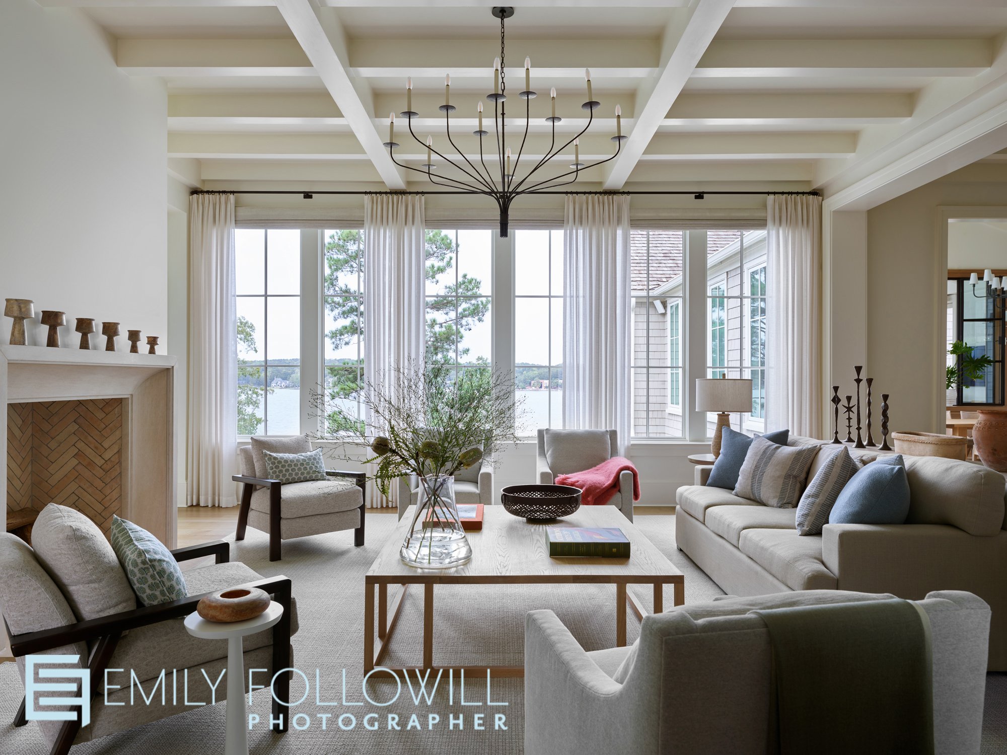 Beautiful white, open and airy living room with 6 doors opening to views of Lake Oconee. Designed by The Design Atlelier