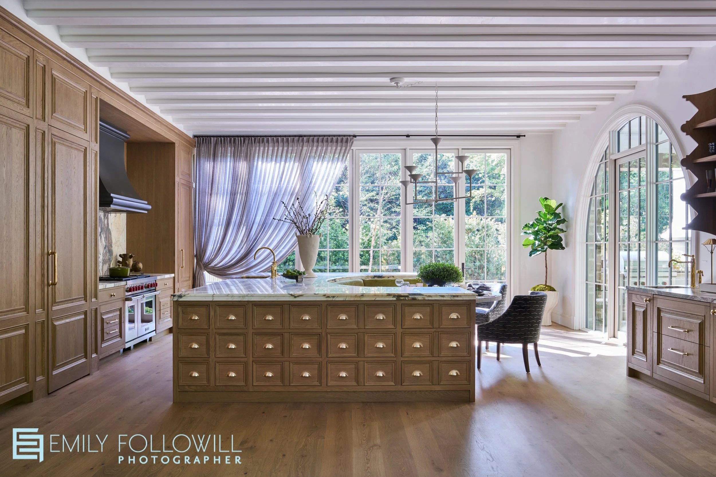 Large Kitchen with custom wooden cabinetry, and elevated fluted ceiling. Shear purple drapes hang around the large iron windows