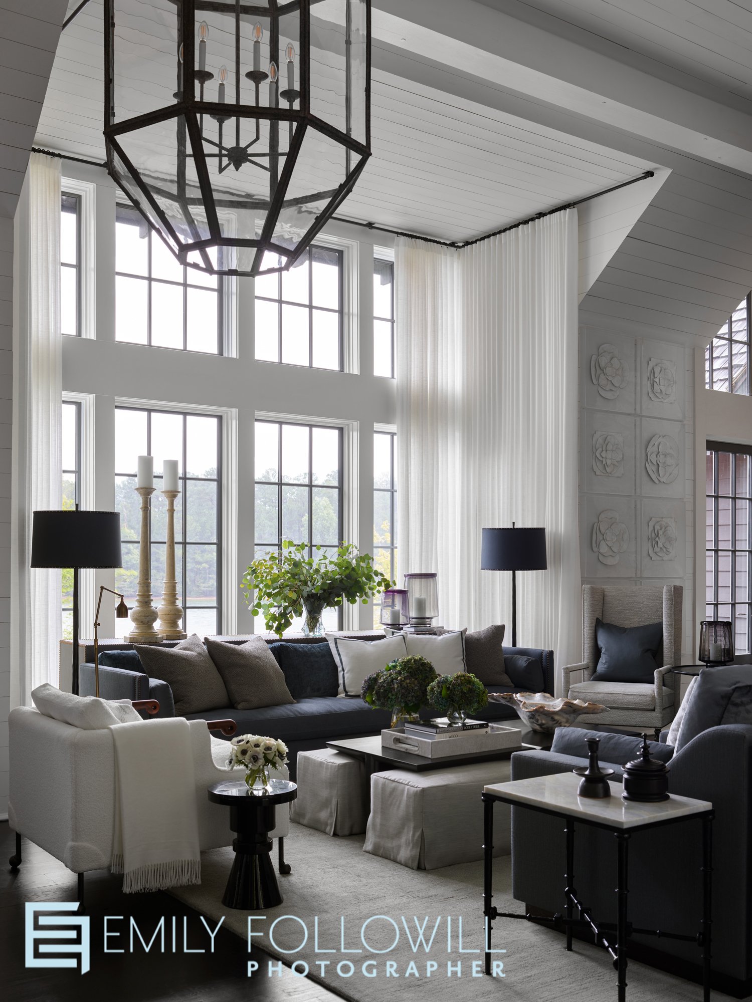 grey and white living room overlooking Lake Martin in Alabama. White sheer drapery surround the large windows. Designed by Susan Ferrier