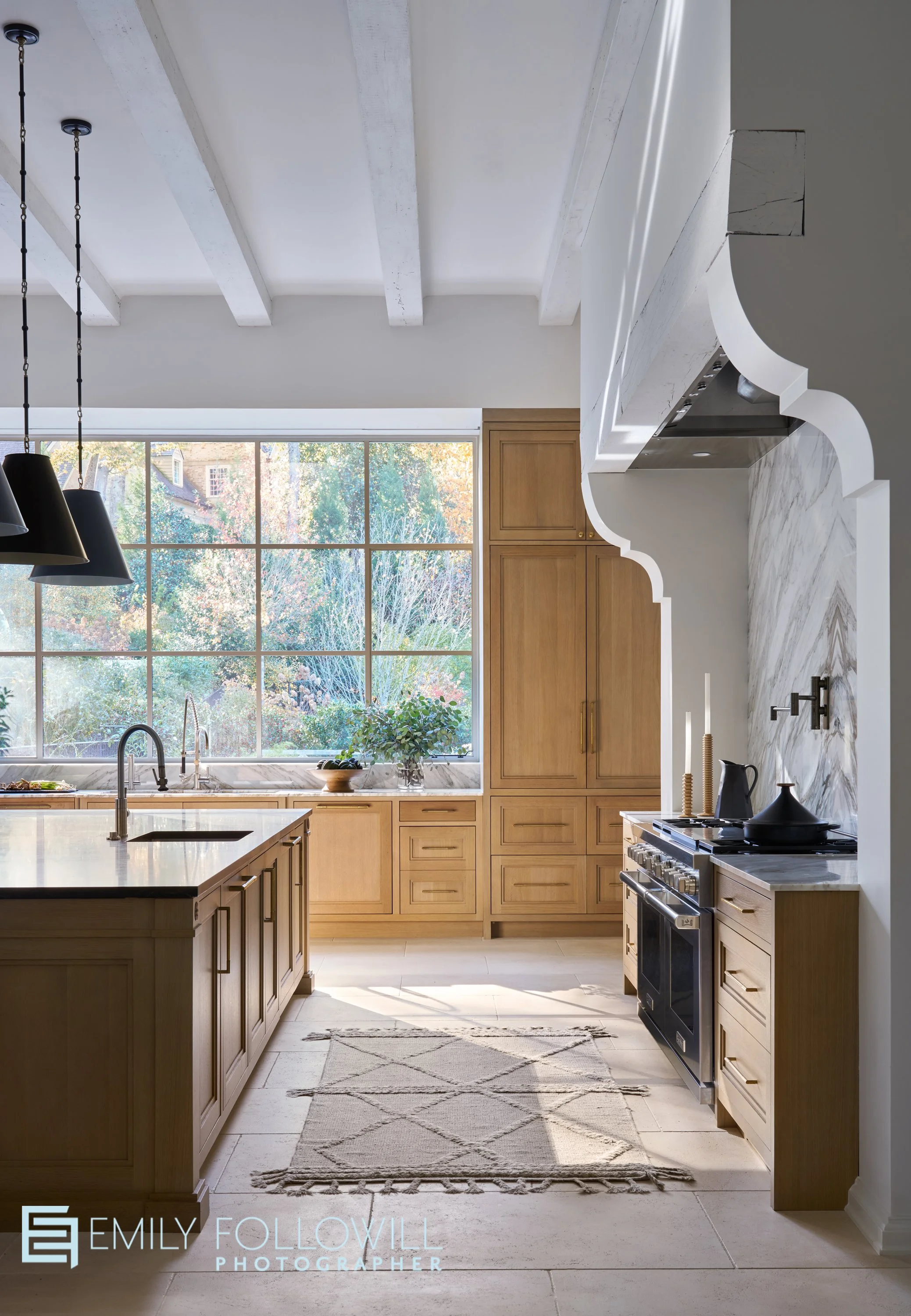 White kitchen, with custom wood cabinetry. Light streams in from the large iron windows over the main sink. Location, Atlanta Georgia. Client, Kingdom Woodworks