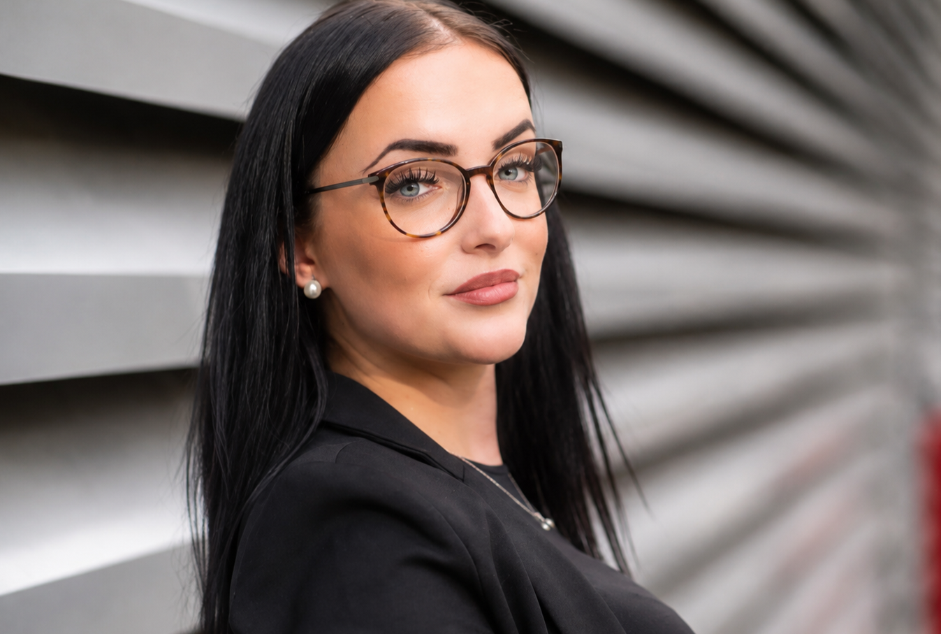 dunkelhharinge junge frau mit Brille vor einem Industrie Hintergrund