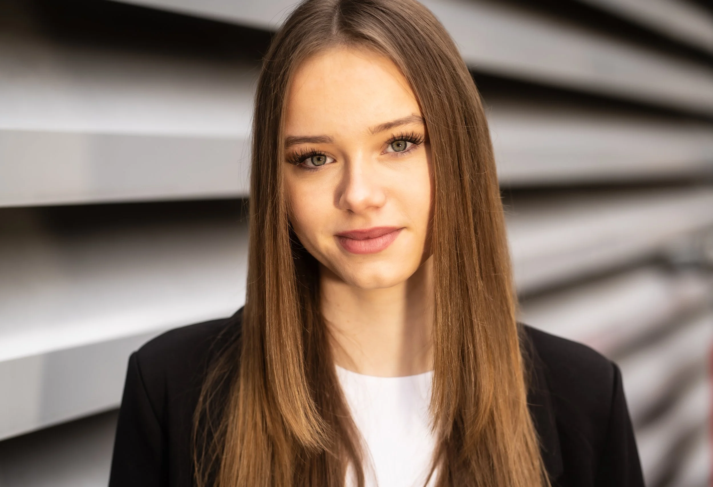 Businessportrait einer Mitarbeiterin mit dunklen Haaren und weißer Bluse, professioneller Cinematic-Look mit unscharfem Hintergrund