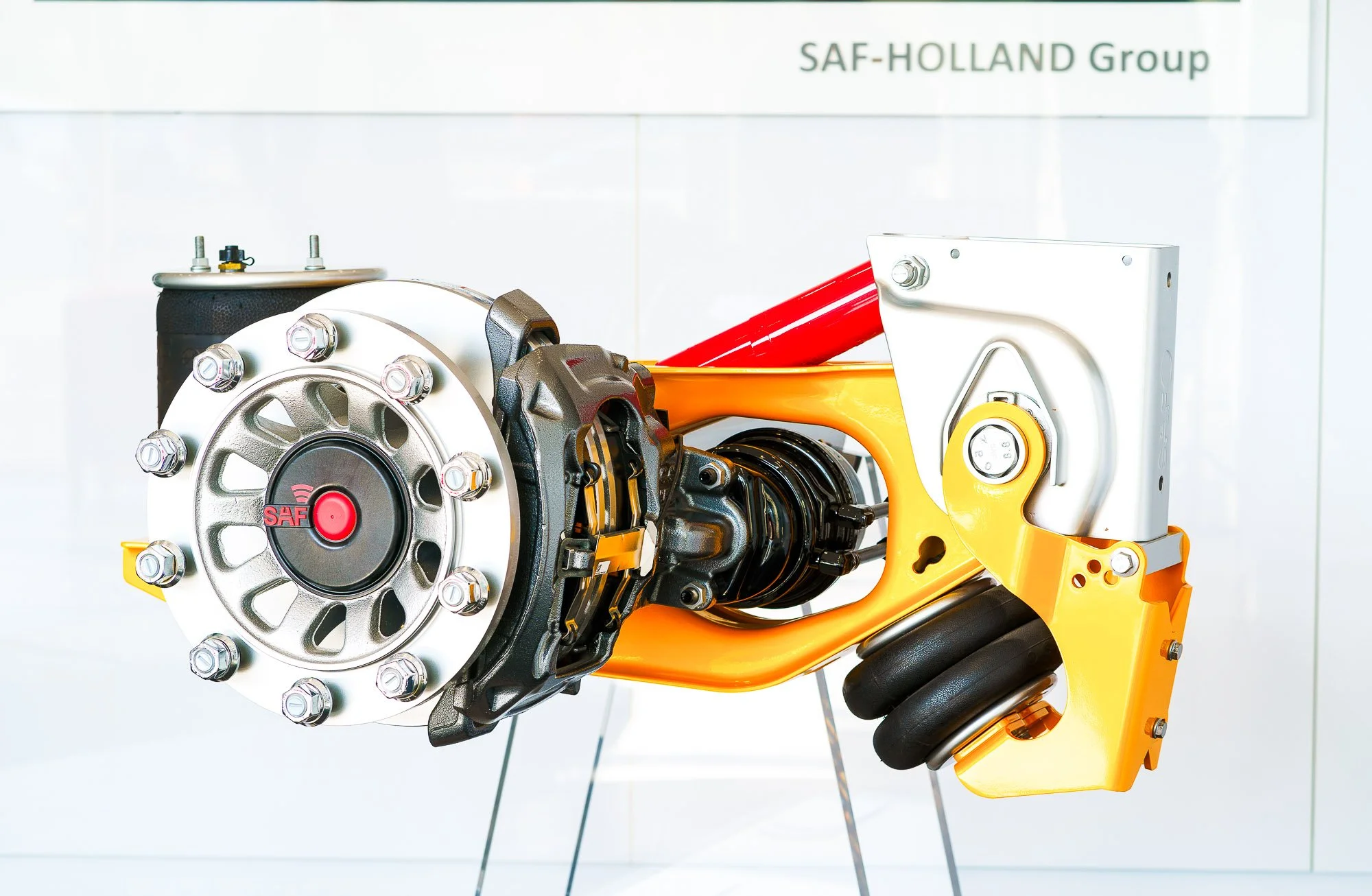 SAF-Holland Group Bremskomponente mit gelber Halterung und technischen Details, Produktfotografie auf weißem Grund