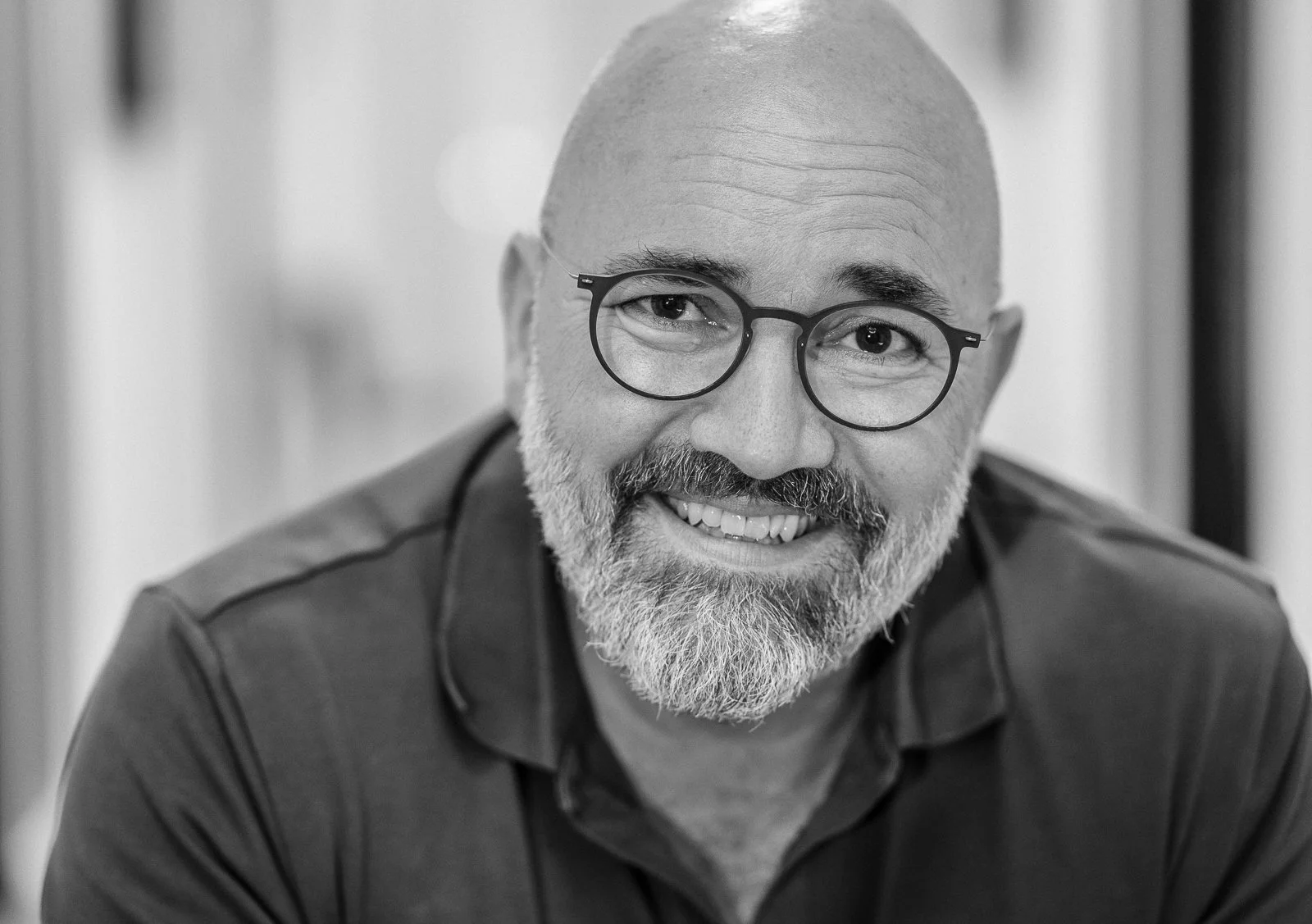 Businessportrait eines Mitarbeiters mit Brille und Bart, minimalistischer grauer Hintergrund