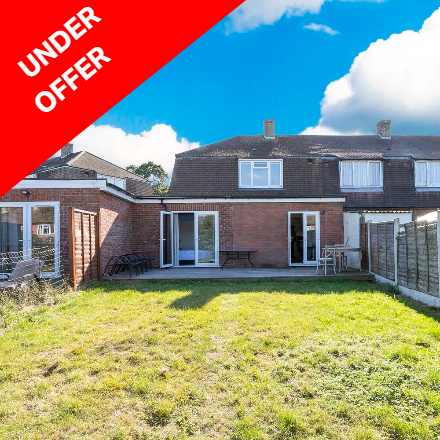 Backyard of a brick house with a lawn and patio area, under a partly cloudy sky, with an red banner that says 'Under Offer' in the top left corner.