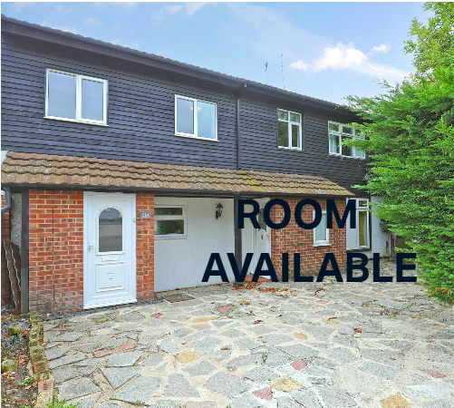 Photo of a two-story townhouse with a brick and white exterior, front door, concrete driveway, green shrubbery on the side, and text overlay that reads 'Room Available'.
