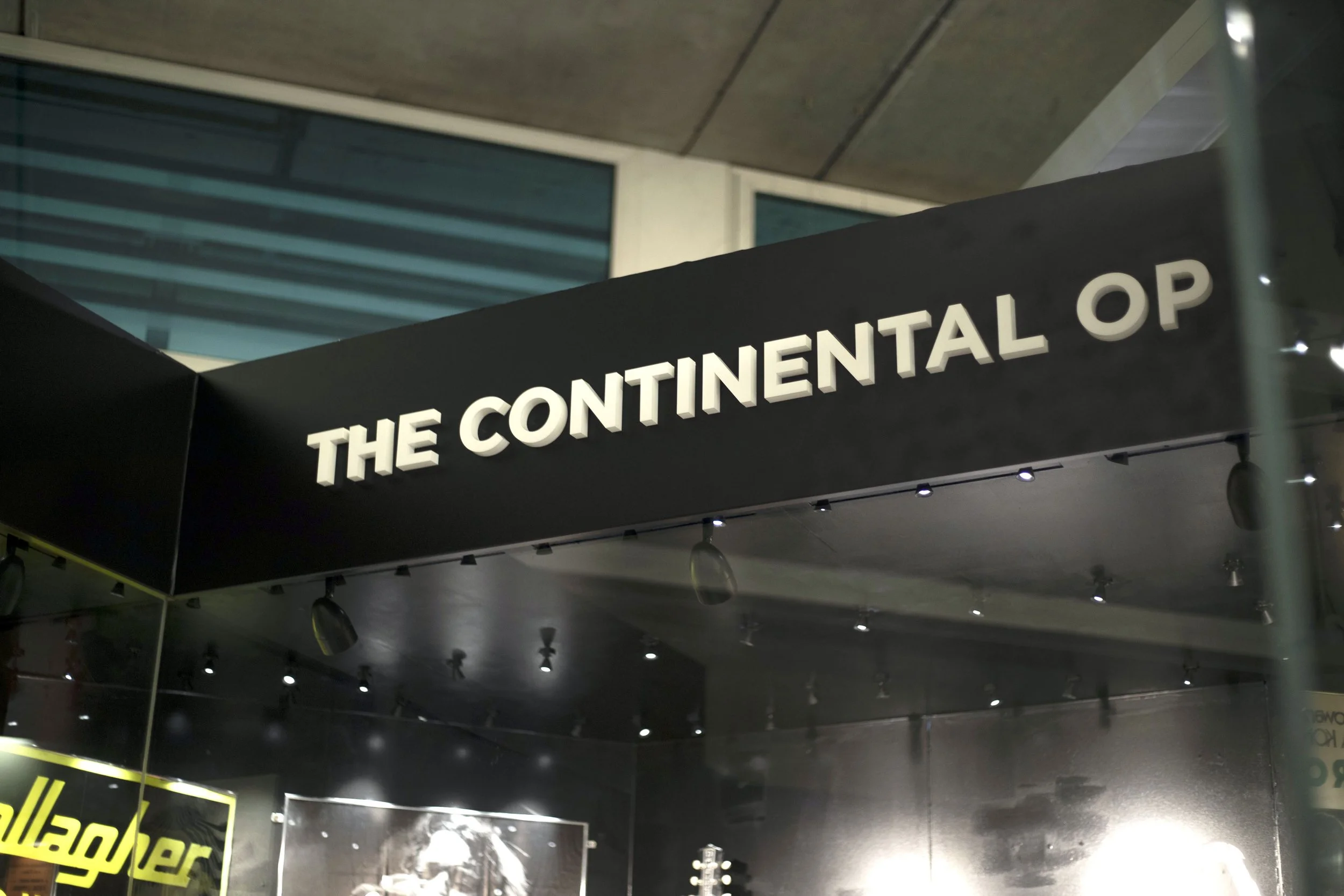 Sign that reads 'The Continental Op' at an indoor venue.
