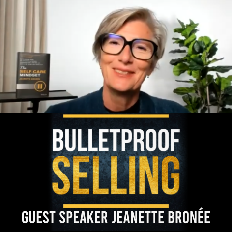 A woman with short gray hair and glasses smiling during a virtual presentation, with a book titled "The Self-Care Mindset" behind her and a green plant on her right.