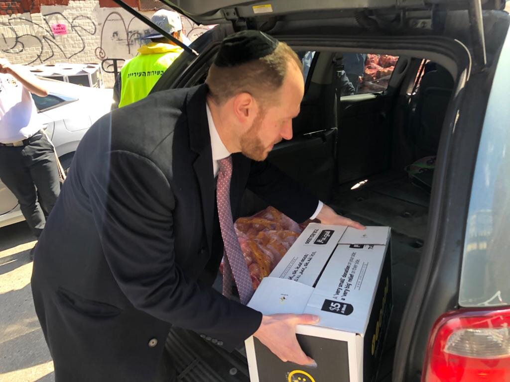 David Greenfield putting a box of food donations into the trunk of a car