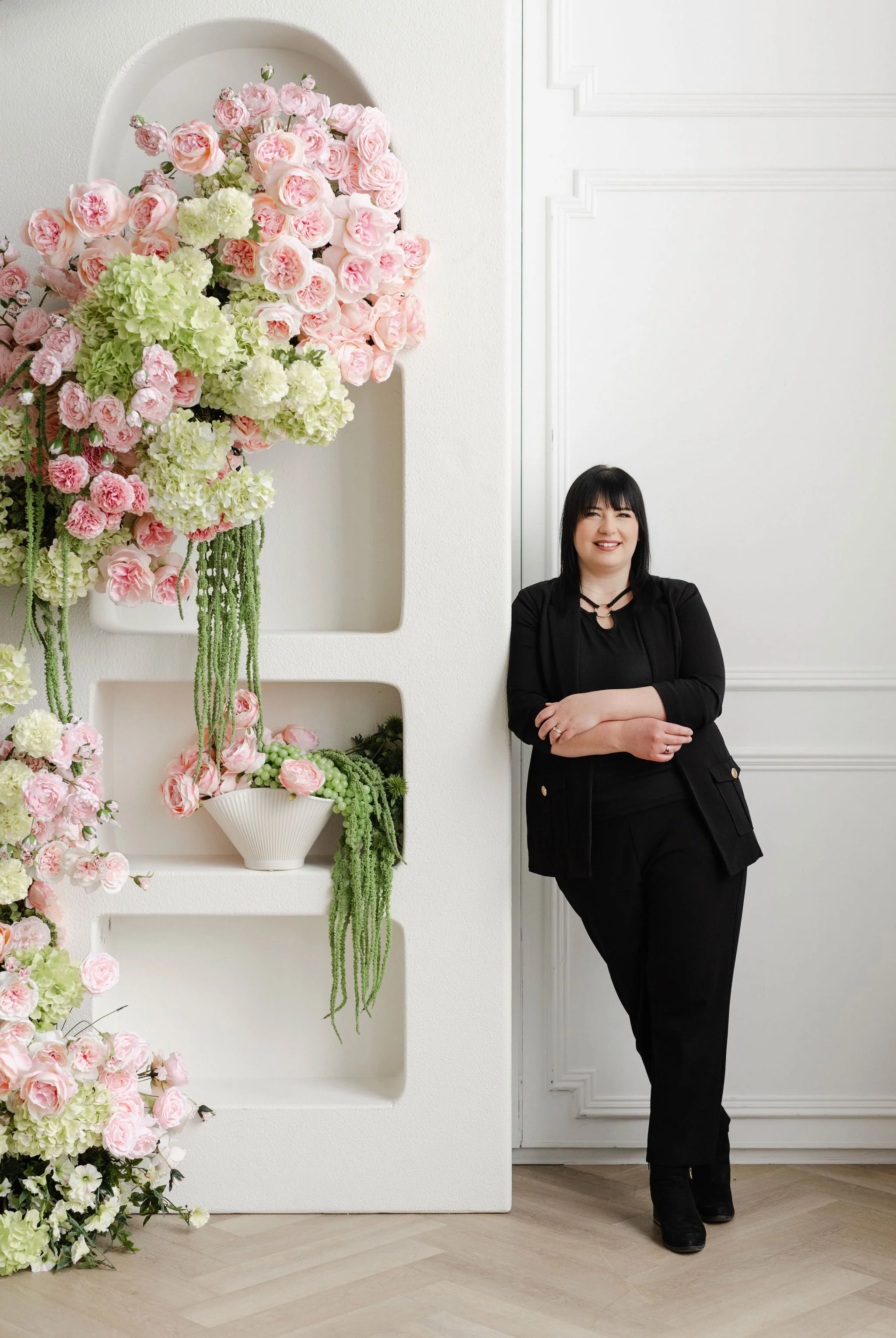 Teresa with long black hair smiling outdoors in front of a lake and autumn trees.