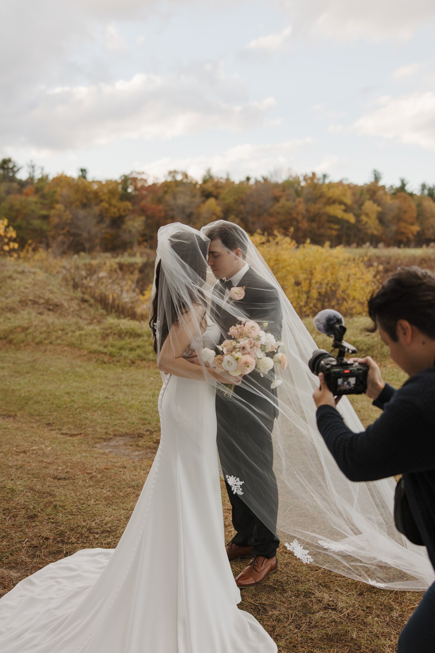 tuan, wedding videographer taking a video of bride and groom within their veil during portrait hour